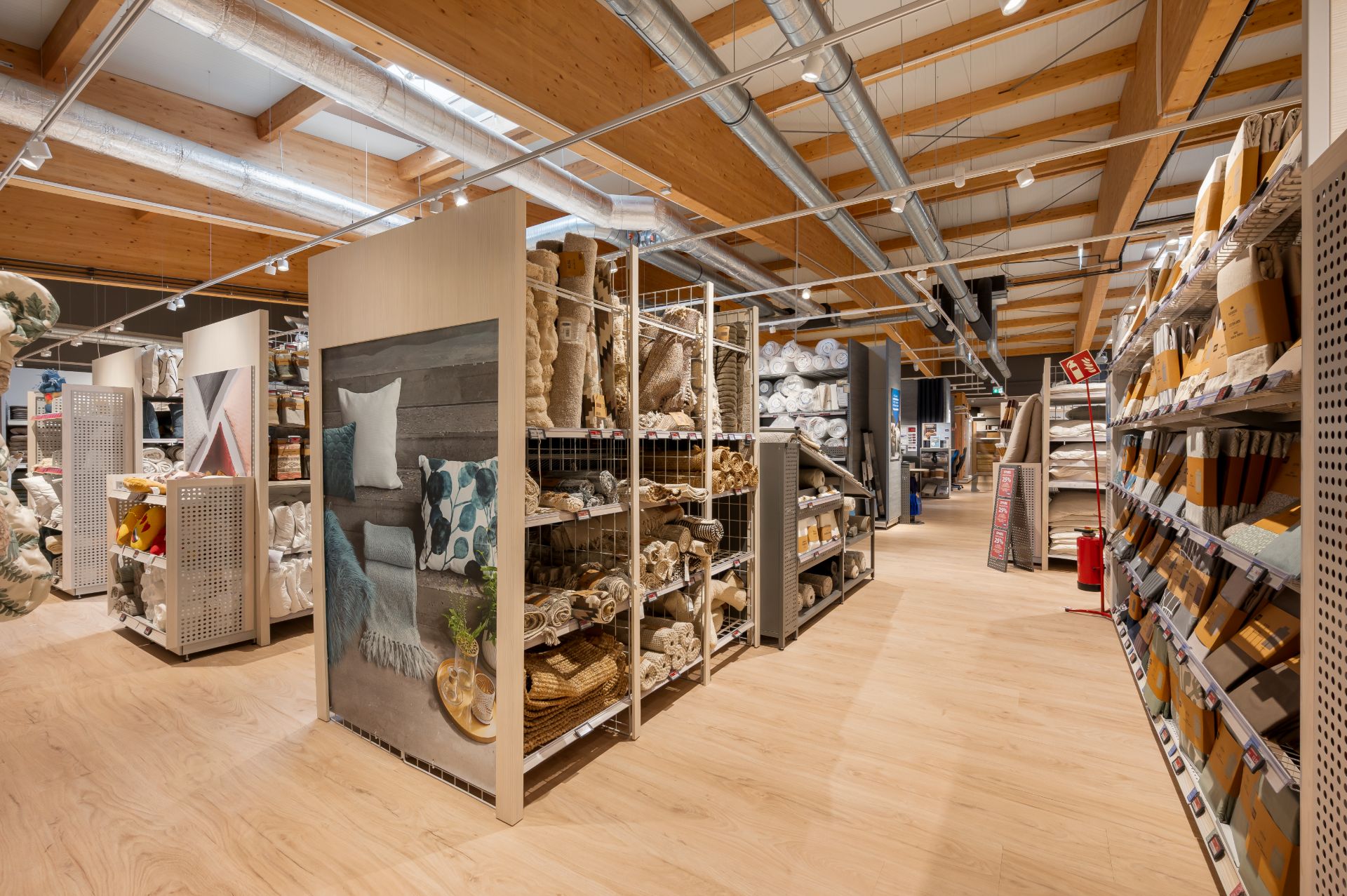 Ein Geschäft mit Holzdecke, Regalen voller Kissen, Decken und Teppichen.