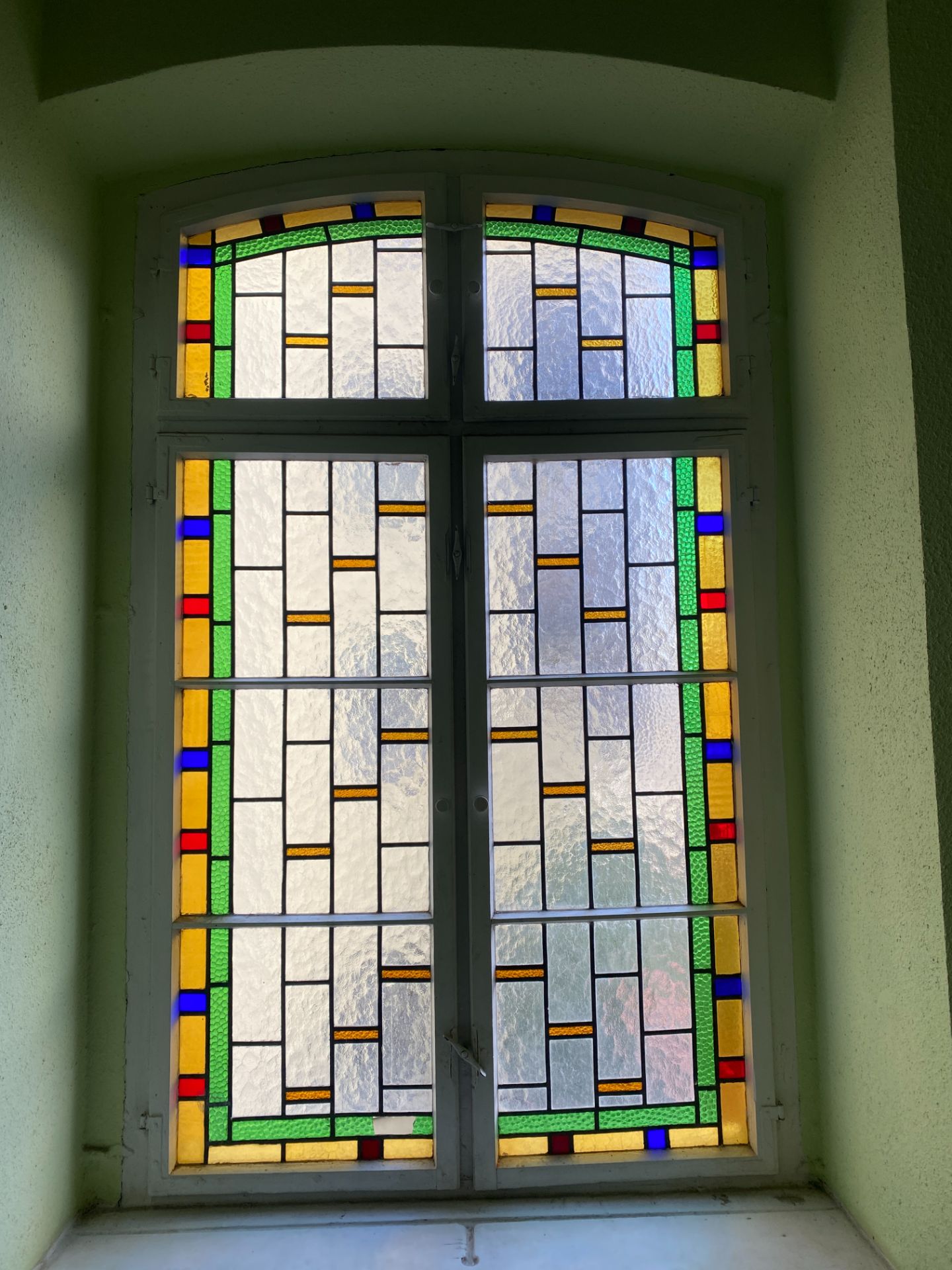 Buntglasfenster mit rechteckigen Mustern in Gelb, Grün, Blau und Rot.