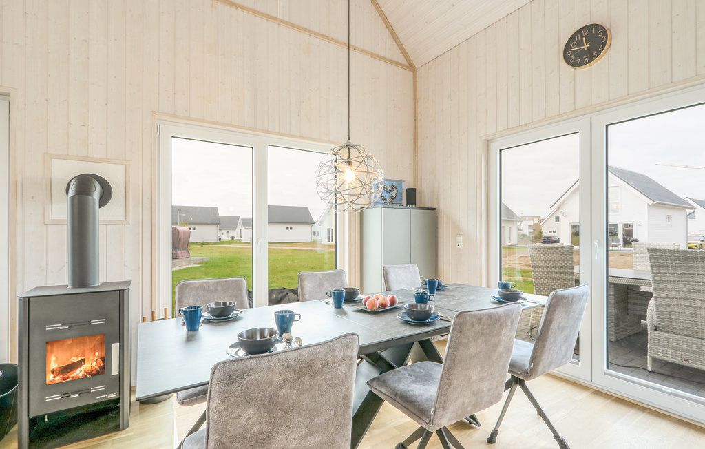 Heller Essbereich mit gedecktem Tisch, Kaminofen und Blick nach draußen durch große Fenster.
