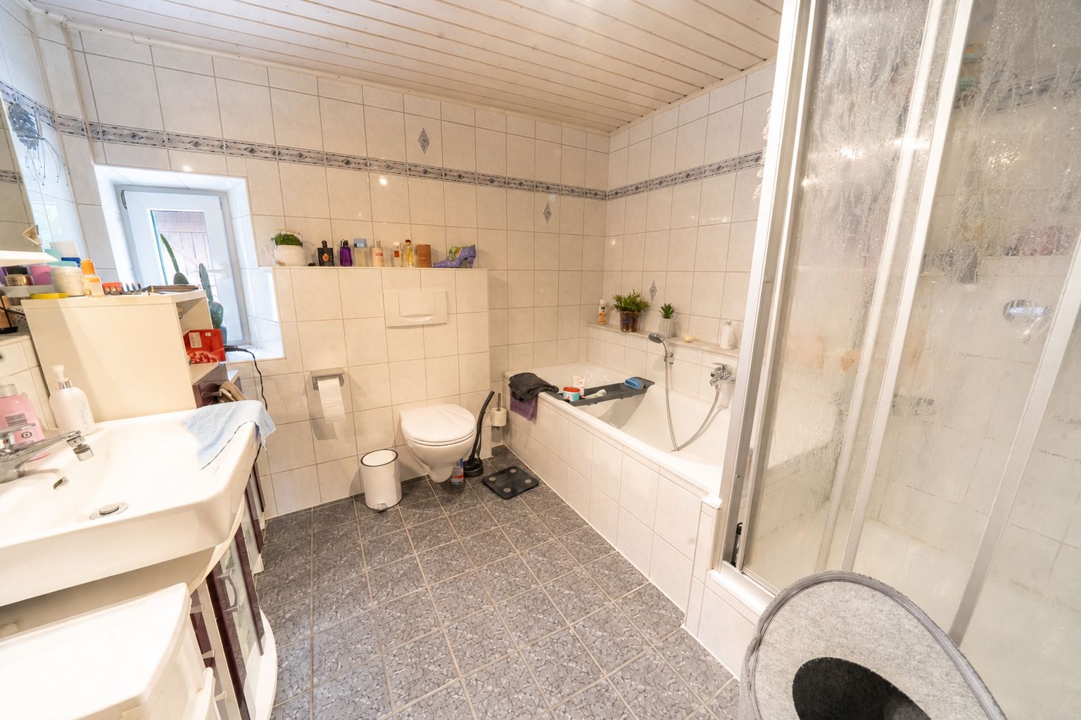 Helles Badezimmer mit Dusche, Badewanne, Toilette, Waschbecken und gefliestem Boden.