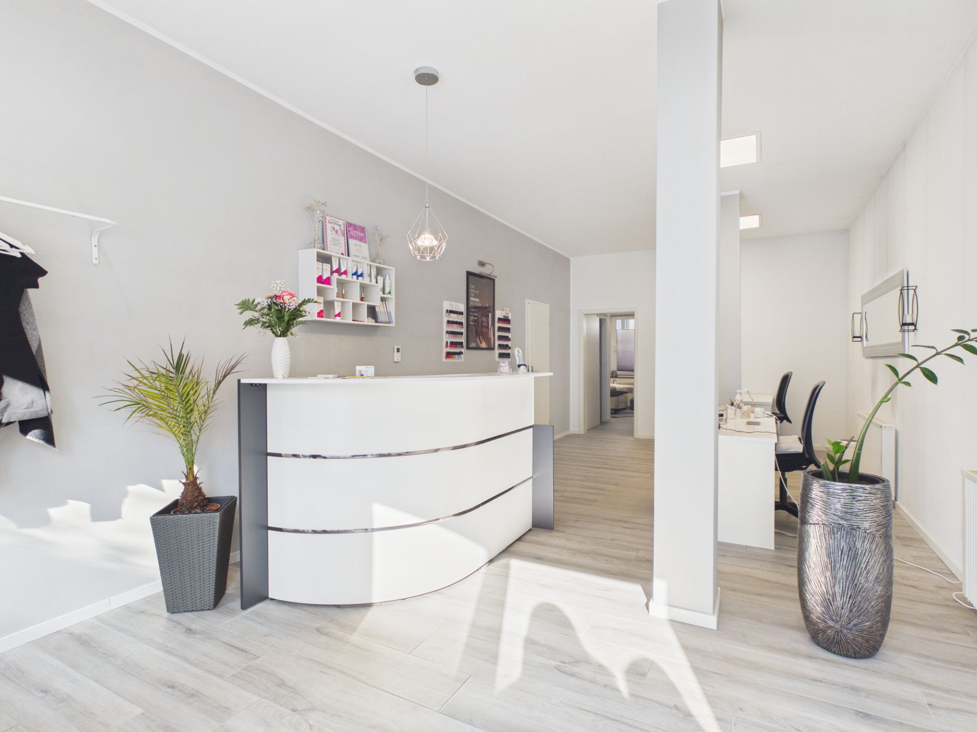 Heller Raum mit geschwungenem Tresen, Pflanzen und modernem Interieur.