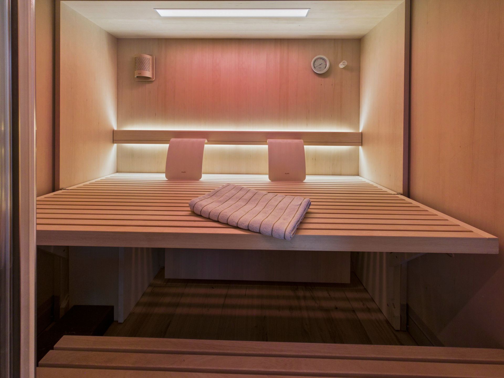 Moderne private Sauna mit Holzbank, zwei Rückenlehnen und einem Handtuch.