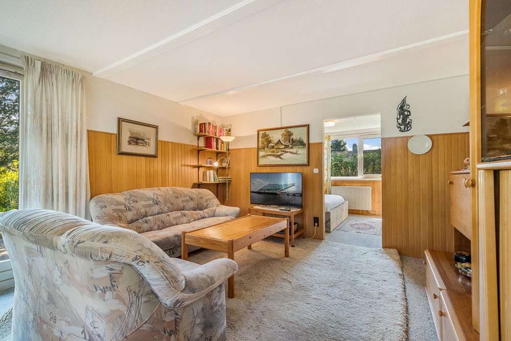 Wohnzimmer mit gemusterten Sofas, Holztisch, Fernseher und Holzwandverkleidung.