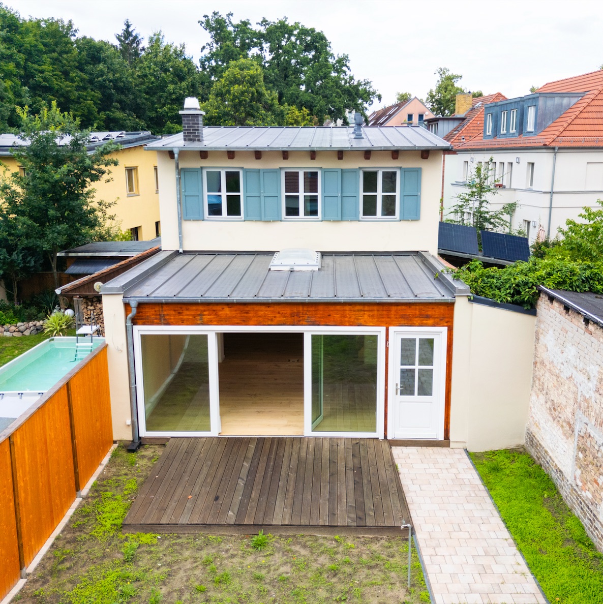 Haus mit Terrasse, Glastüren und kleinem Garten, von oben aufgenommen.