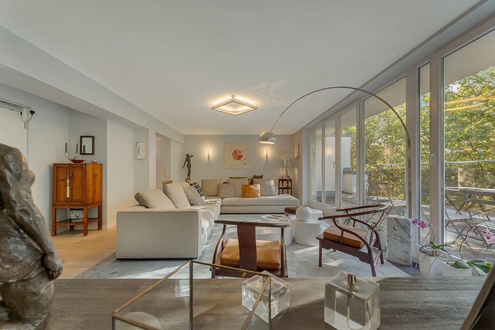 Helles Wohnzimmer mit großem Sofa, Glastüren zum Balkon und modernen Möbeln.