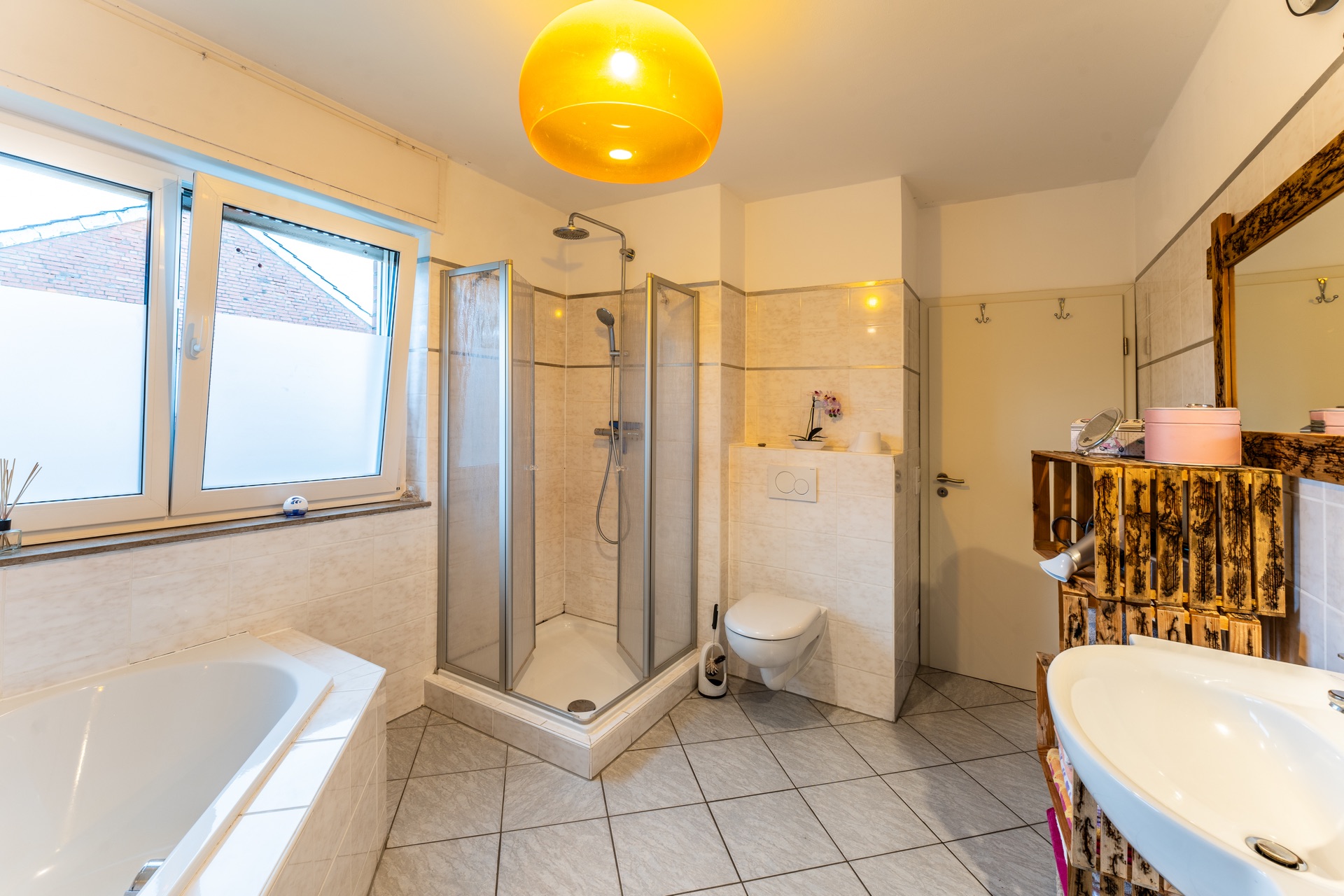 Helles Badezimmer mit Dusche, Badewanne, WC, Waschbecken und großem Fenster.