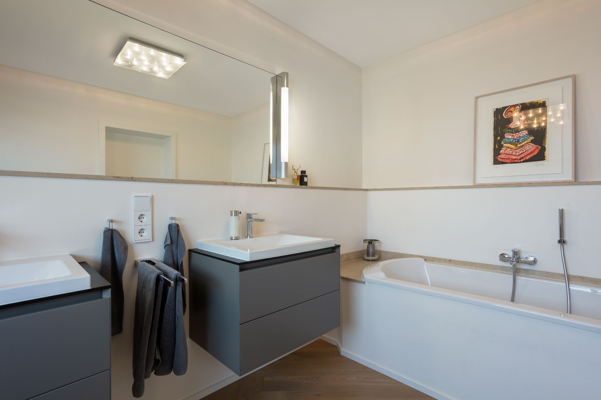 Modernes Badezimmer mit zwei Waschbecken, Badewanne, großem Spiegel und Wandbild.