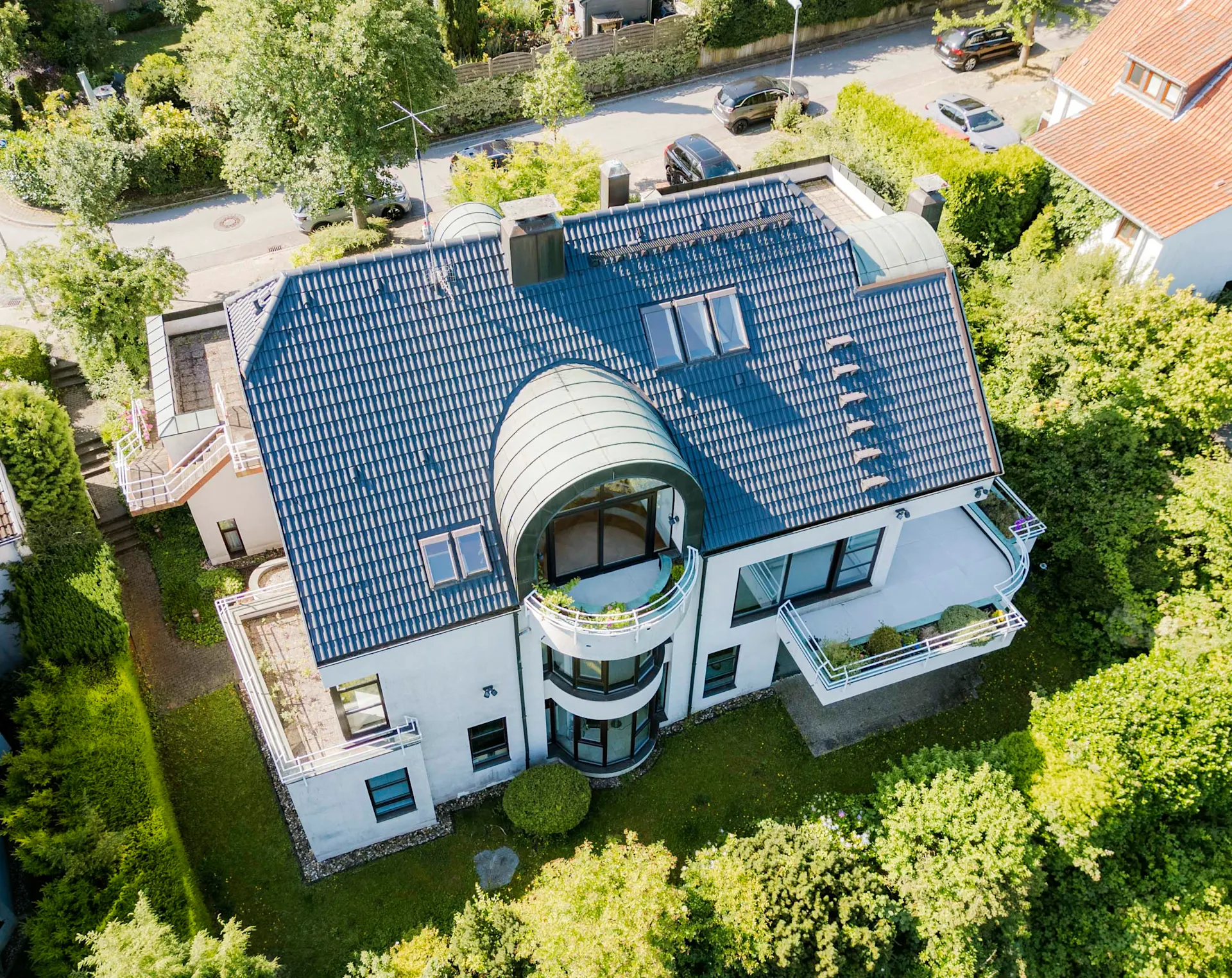 Luftaufnahme eines modernen Wohnhauses mit blauem Dach und mehreren Balkonen.