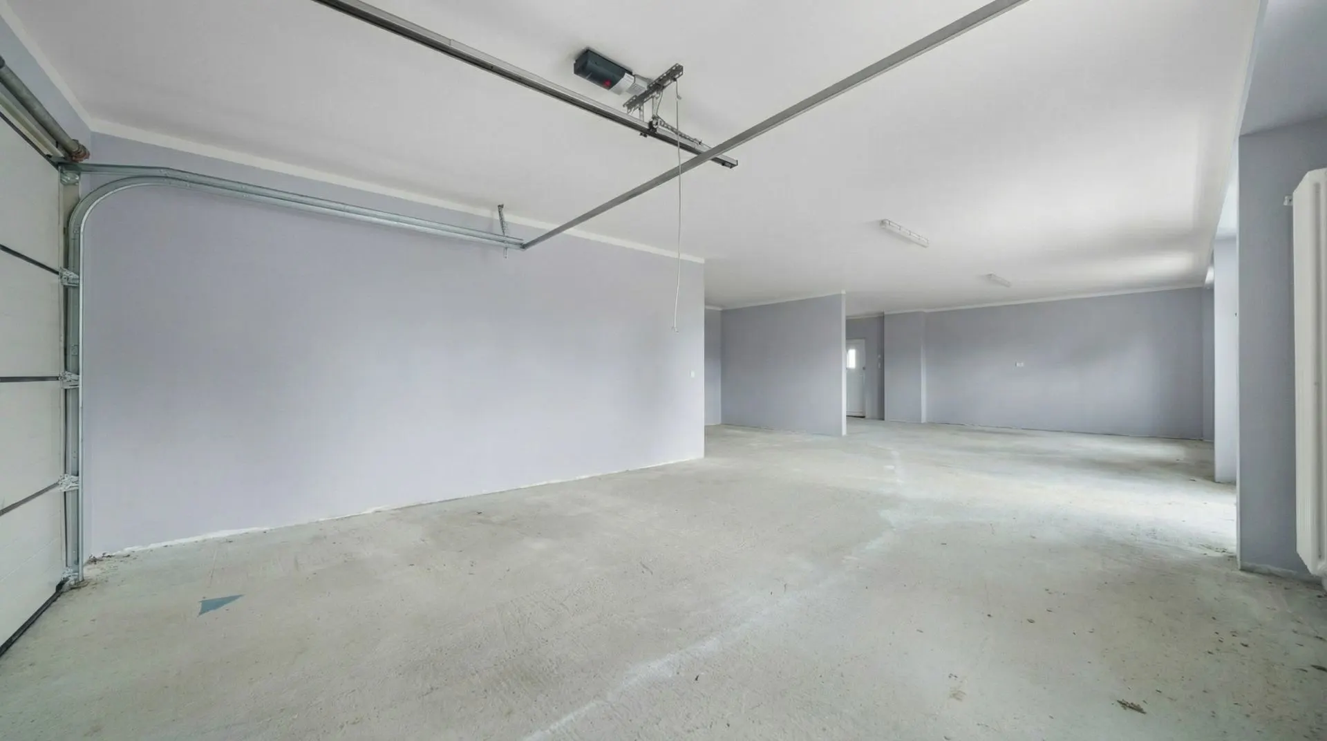 Geräumige, leere Garage mit grauen Wänden und Deckenleuchten.