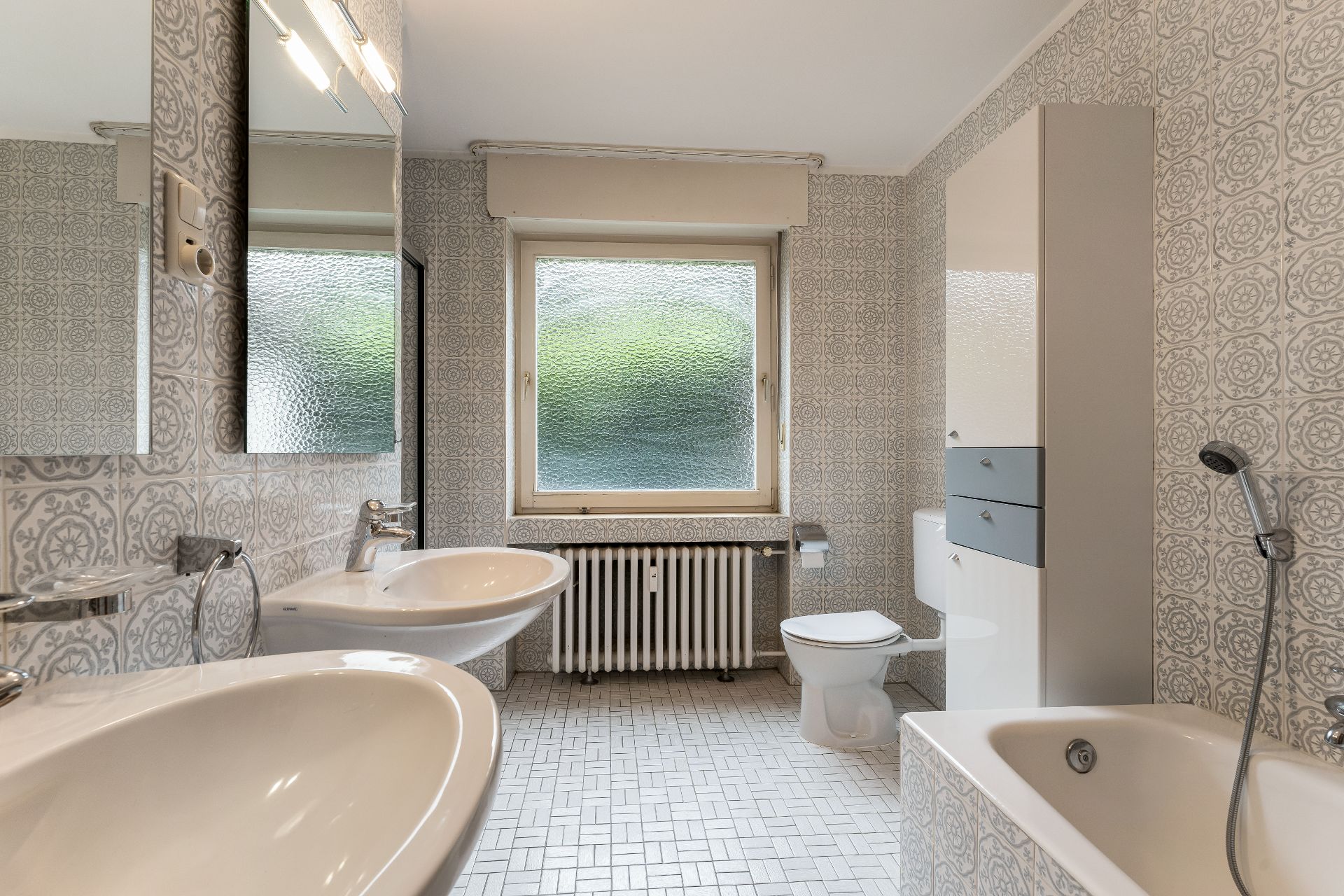 Modernes Badezimmer mit zwei Waschbecken, Toilette, Badewanne und großem Fenster.