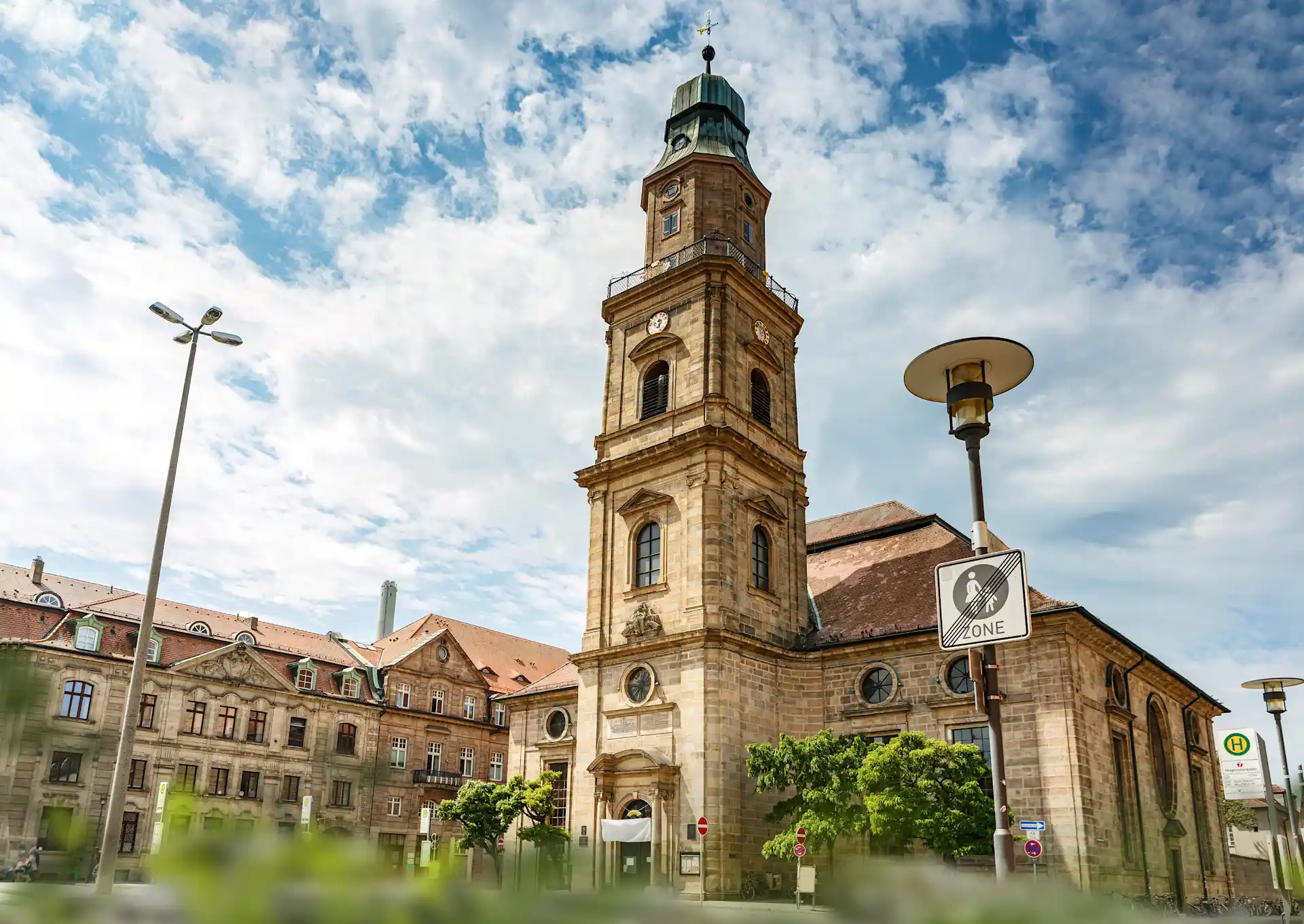 Großes, historisches Gebäude mit Uhrturm und Rundfenstern auf einem öffentlichen Platz.