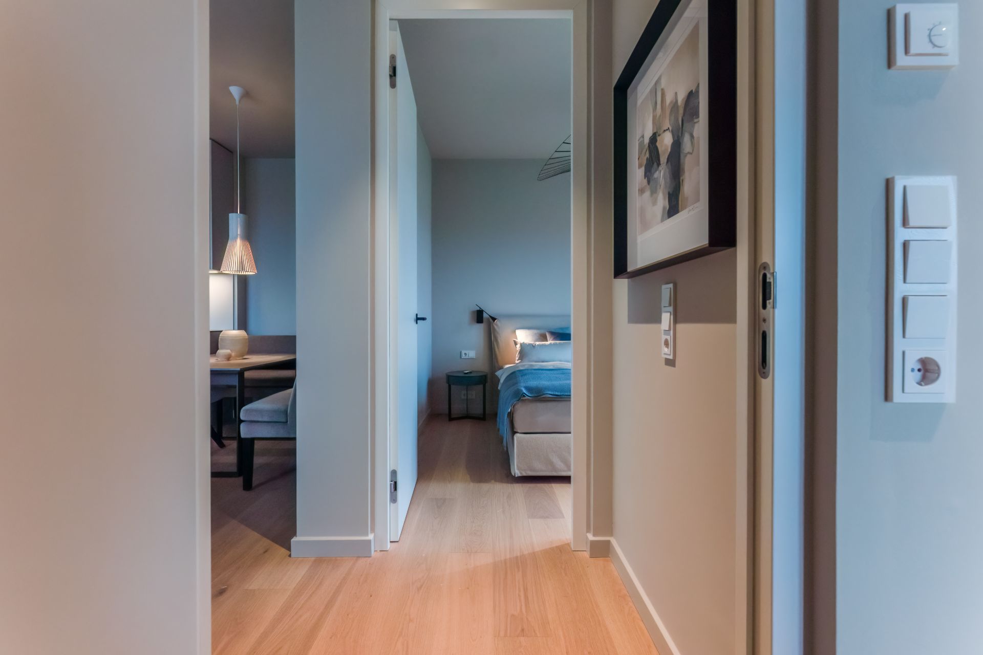 Flur mit Blick ins Schlafzimmer und Esszimmer, Holzfußboden und Wandbild sichtbar.