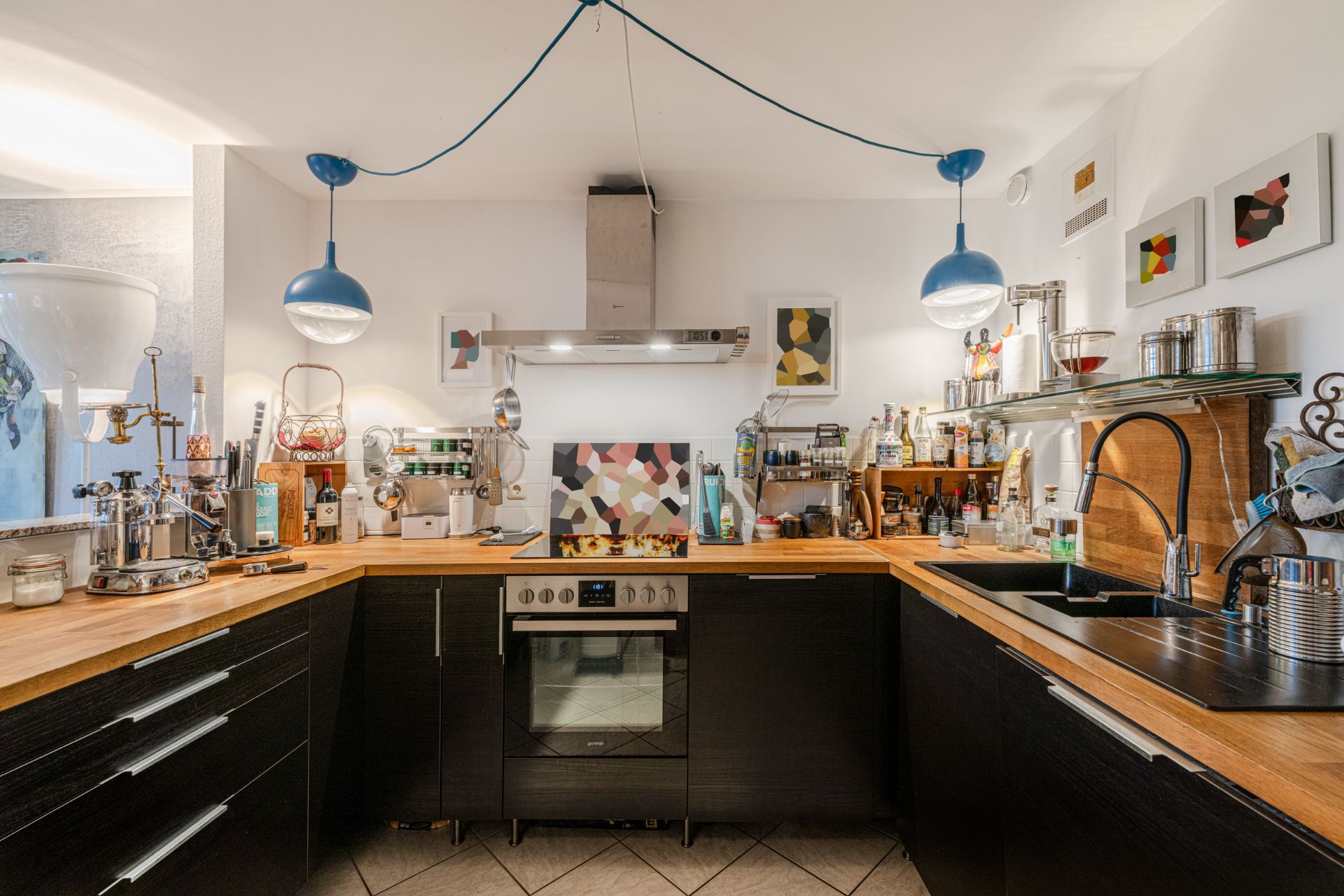 Moderne Küche mit Holzarbeitsplatte, Herd, Spüle und Hängelampen.