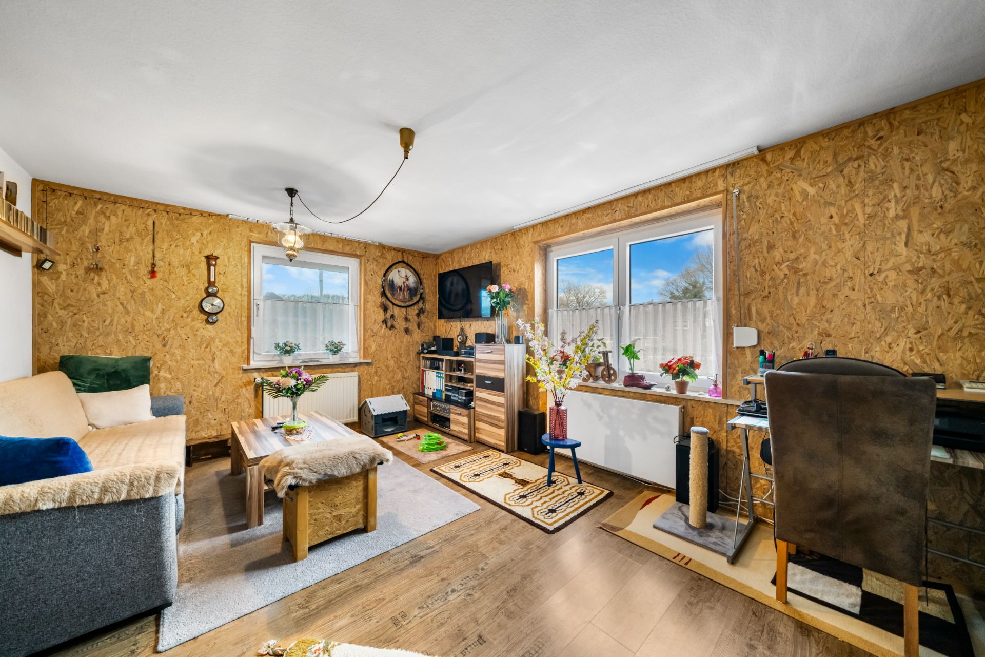 Wohnzimmer mit Sofa, Couchtisch, Fernseher und Pflanzen auf Fensterbank.
