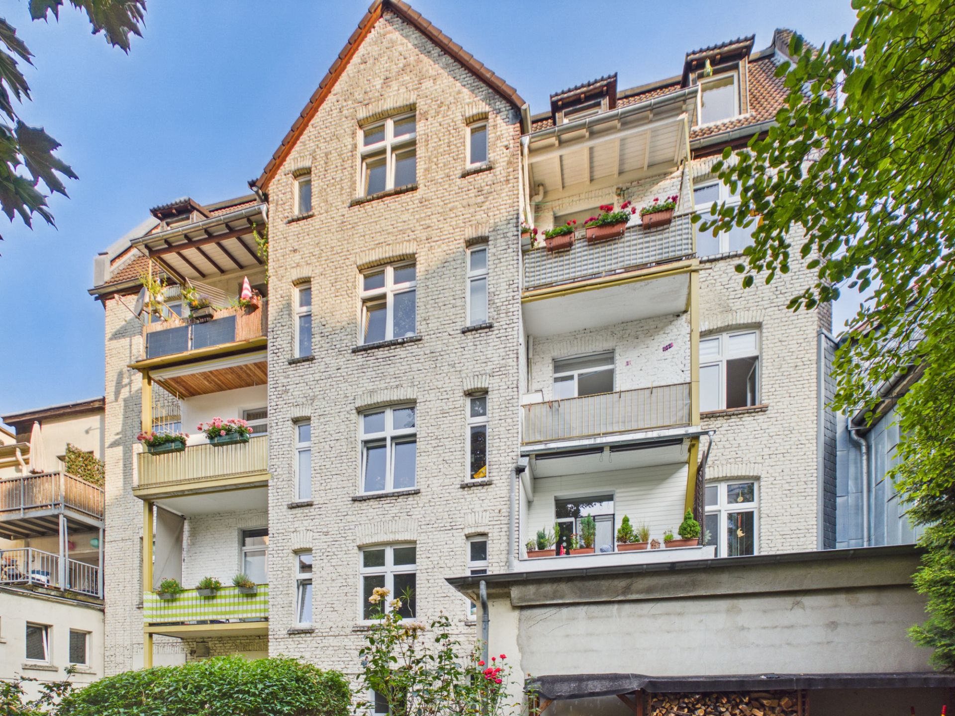 Mehrstöckiges Wohnhaus mit mehreren Balkonen und Blumenkästen an der Fassade.
