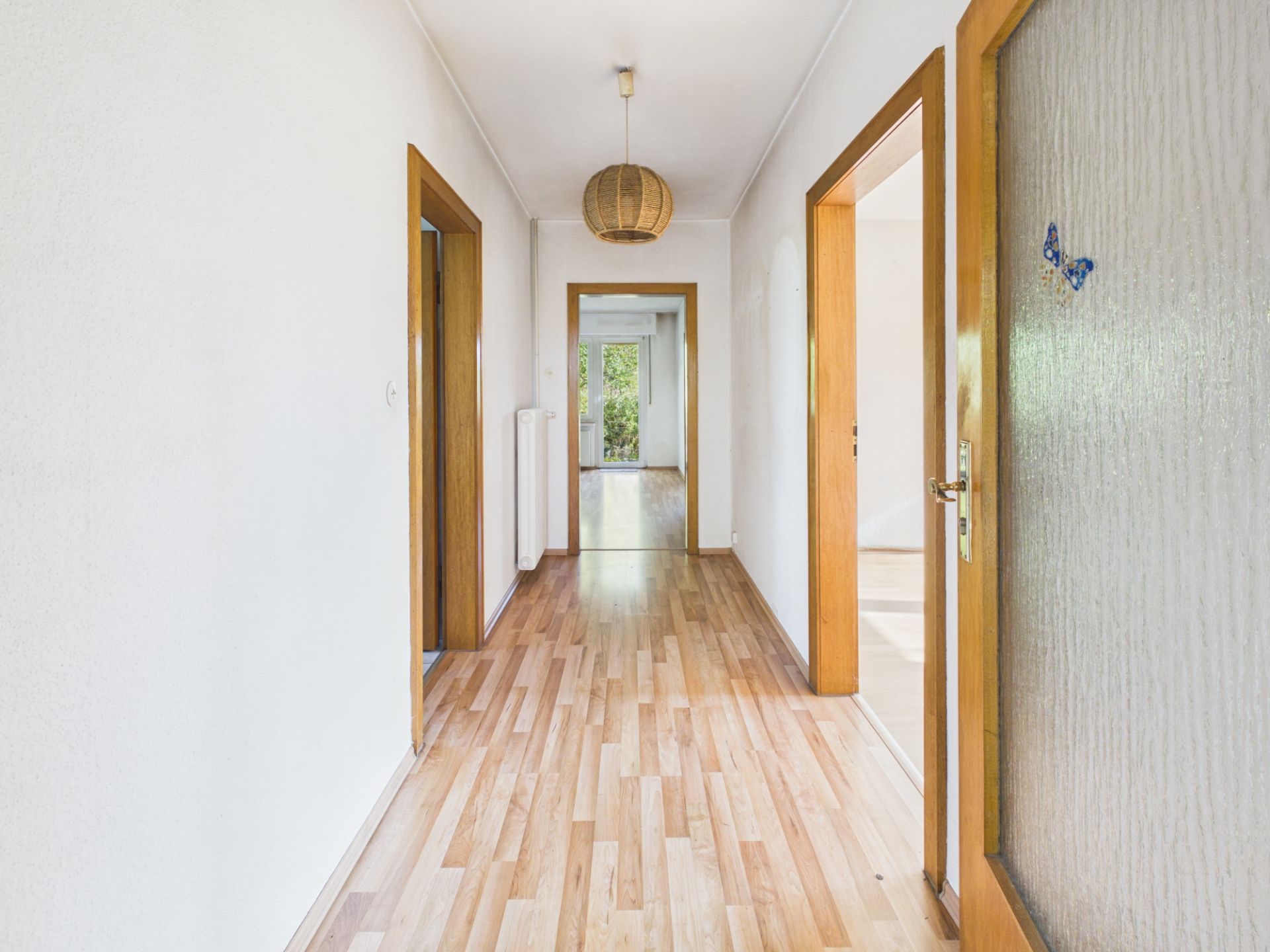 Heller Flur mit Holzfußboden und mehreren offenen Türen in einer Wohnung.
