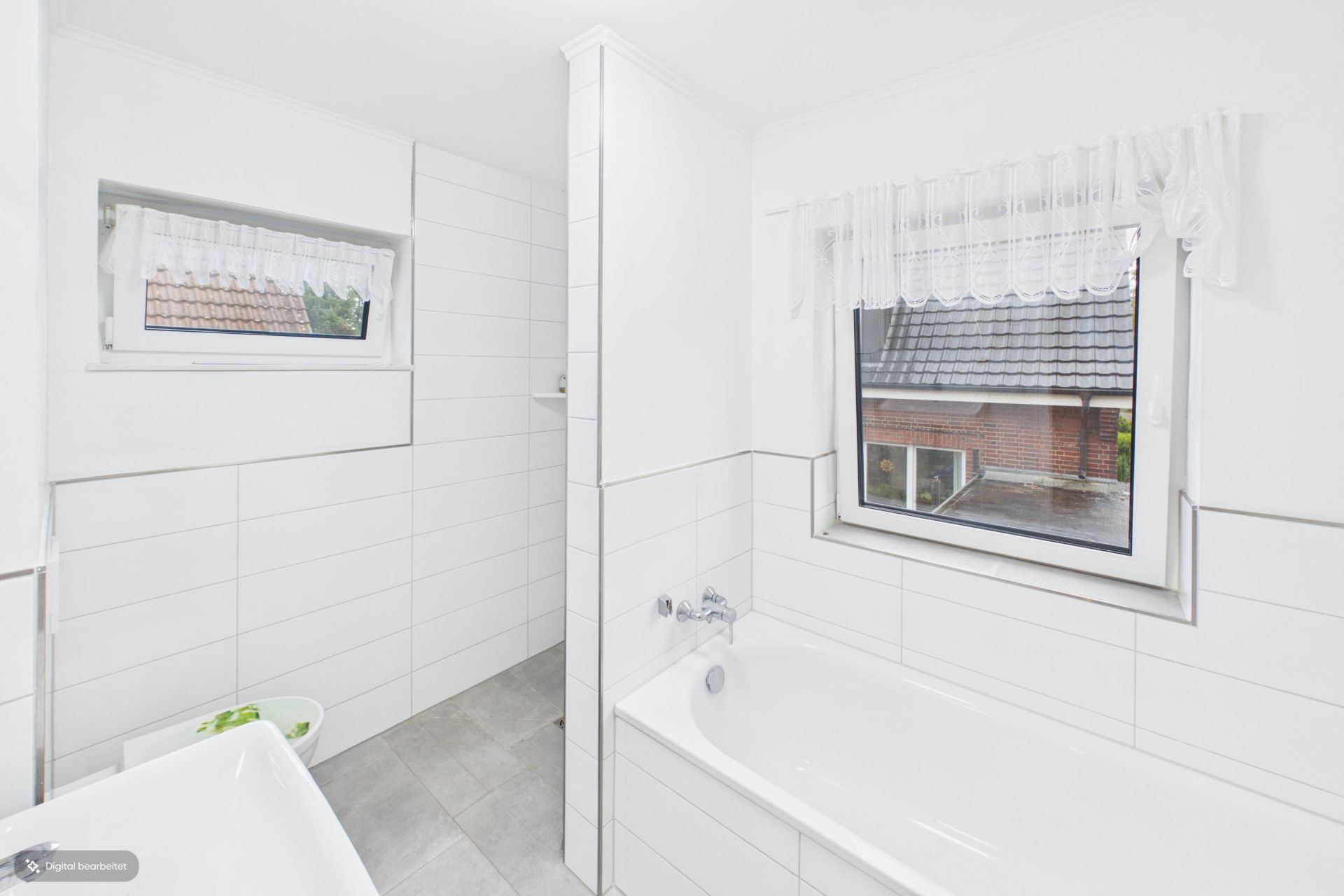 Helles Badezimmer mit Badewanne, zwei Fenstern und weißen Fliesen.