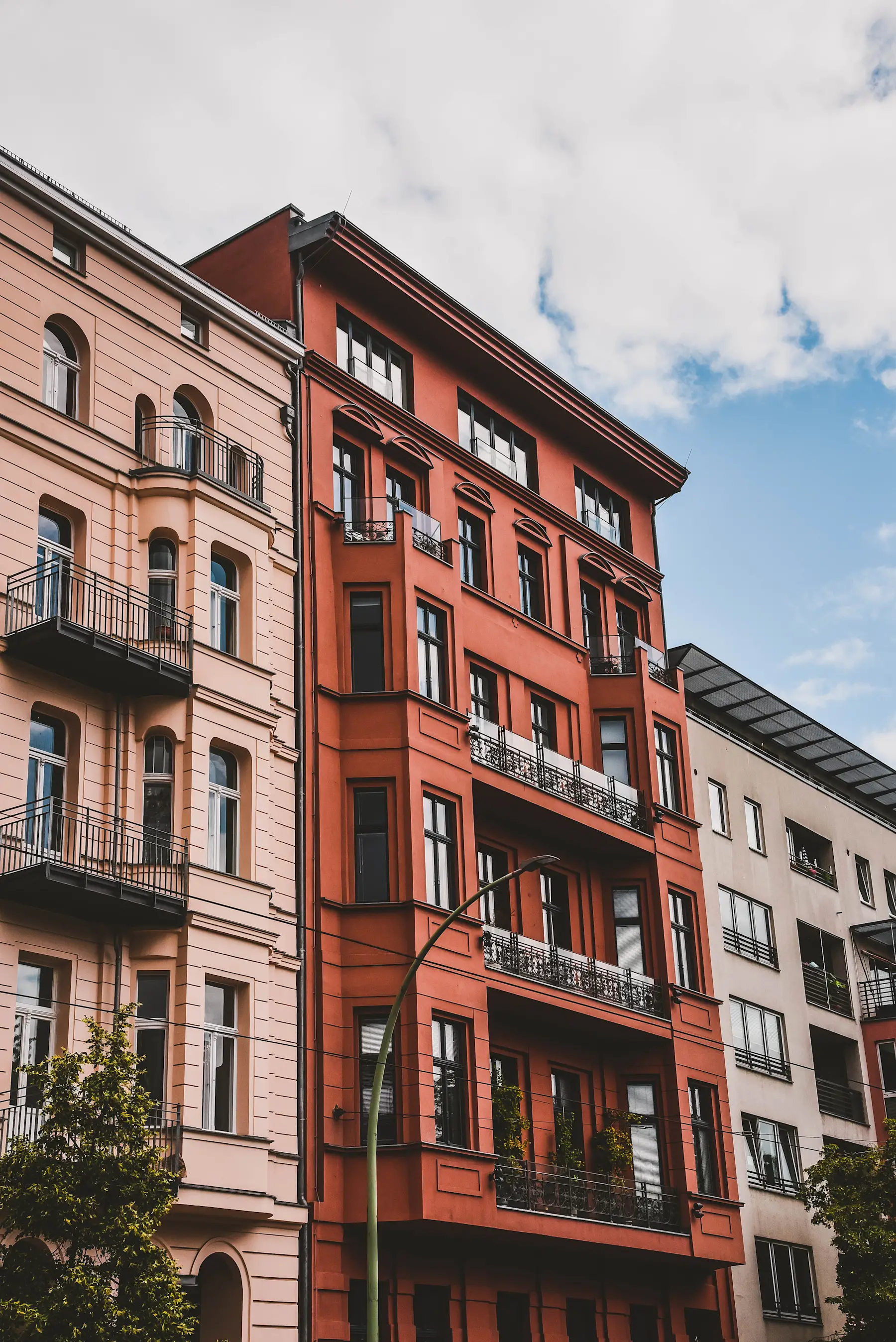 Mehrstöckiges Wohngebäude mit Balkonen und großen Fenstern, rote Fassade.