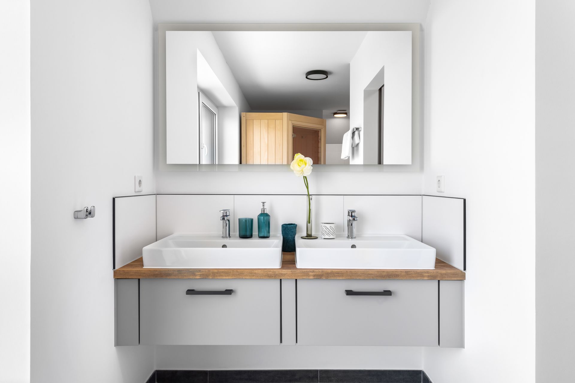 Modernes Badezimmer mit zwei Waschbecken, großem Spiegel und Dekoration auf dem Waschtisch.