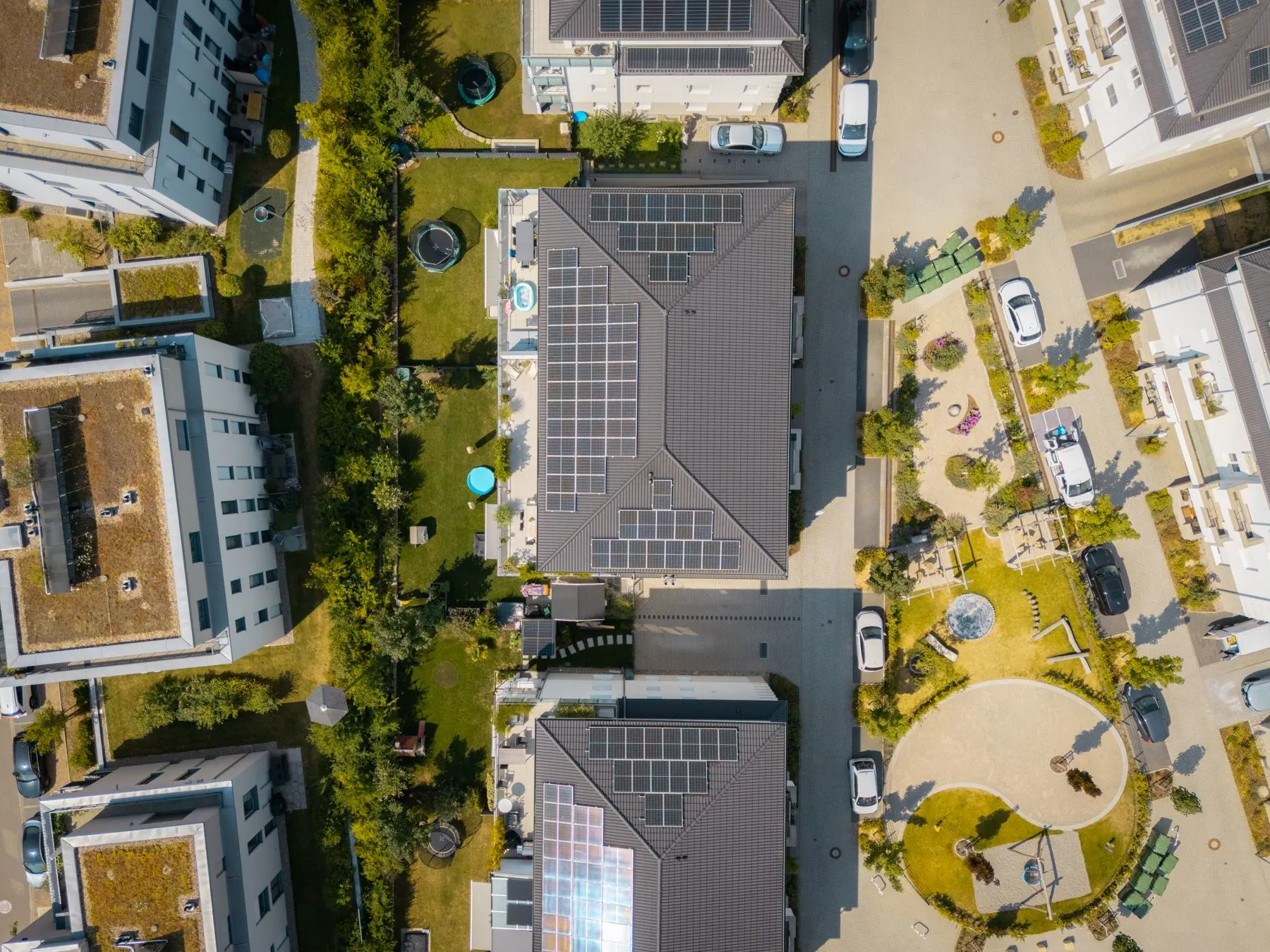 Luftaufnahme von Wohngebäuden mit Solarpanels, Gärten und umliegenden Straßen.