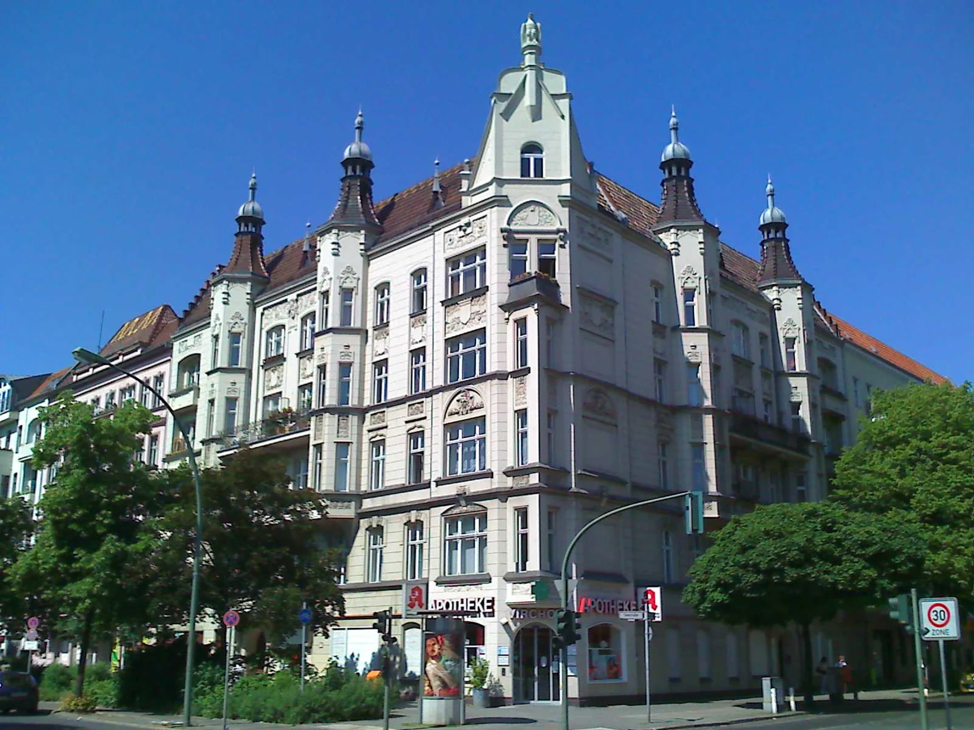 Mehrstöckiges Wohnhaus mit verzierten Fassaden und Türmen an einer Straßenecke.