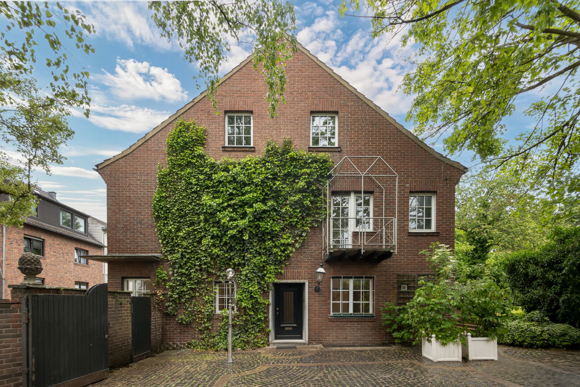 Backsteinhaus mit Efeu an der Fassade, drei Stockwerke, Hof mit Kopfsteinpflaster.