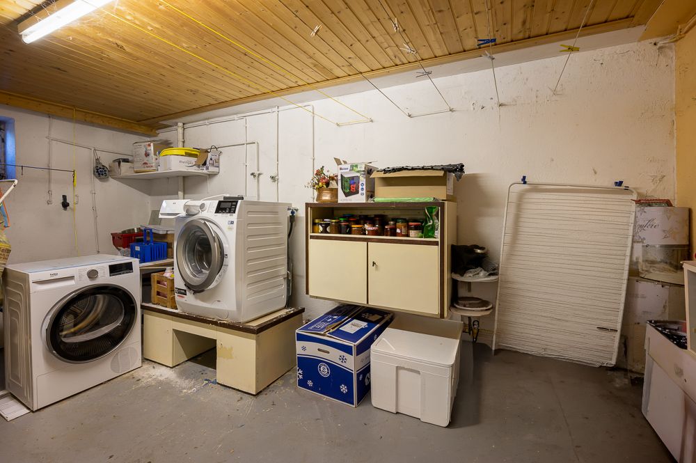 Waschraum mit Waschmaschine, Trockner, Regalen und Aufbewahrungsboxen.