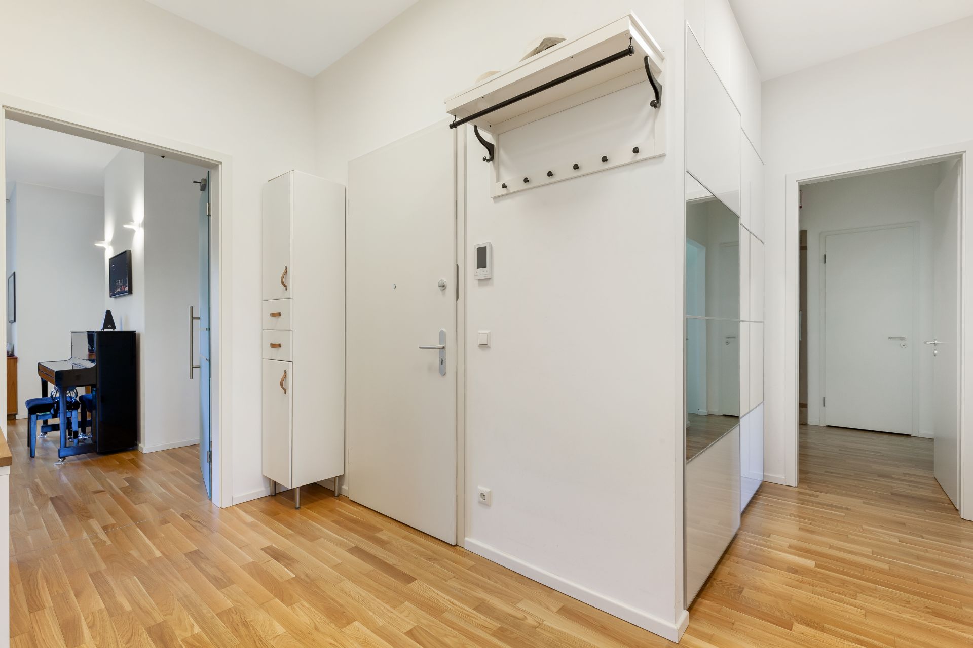 Heller Flur mit Holzboden, Garderobe, Spiegel und Zugang zu mehreren Zimmern.
