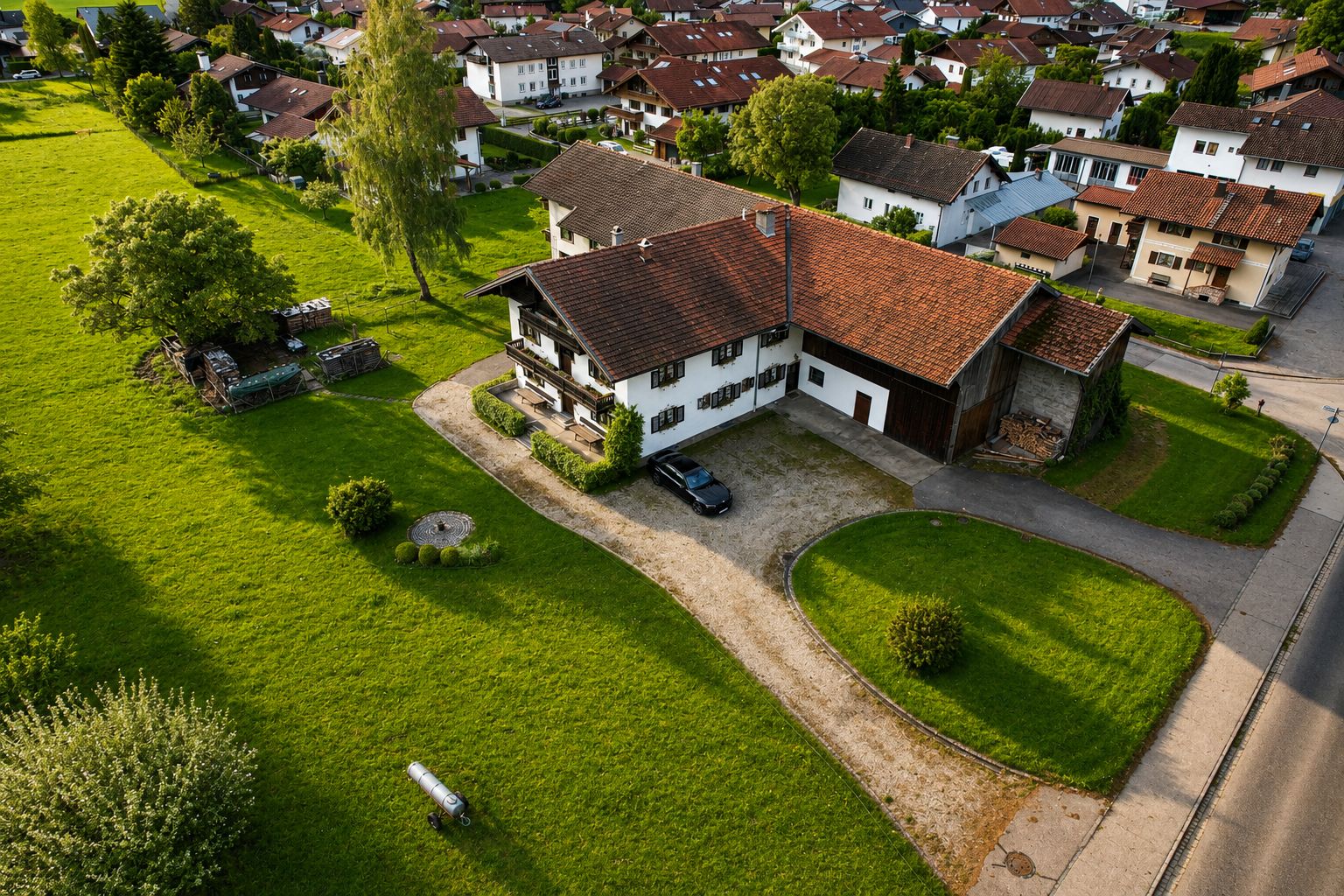 Luftaufnahme eines Wohnhauses mit großem Garten und Auffahrt in einer Siedlung.