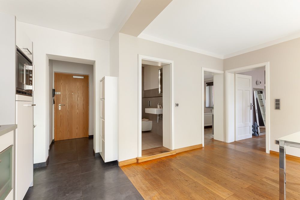 Heller Flur mit Holzboden, Türen zu Bad und weiteren Zimmern, Eingangstür sichtbar.