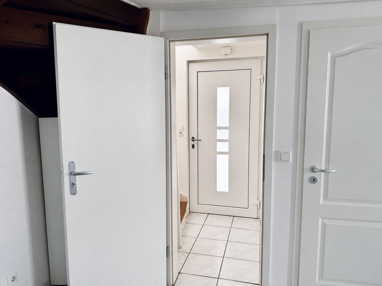 Flur mit weißen Türen und Fliesenboden in einem Wohnhaus.