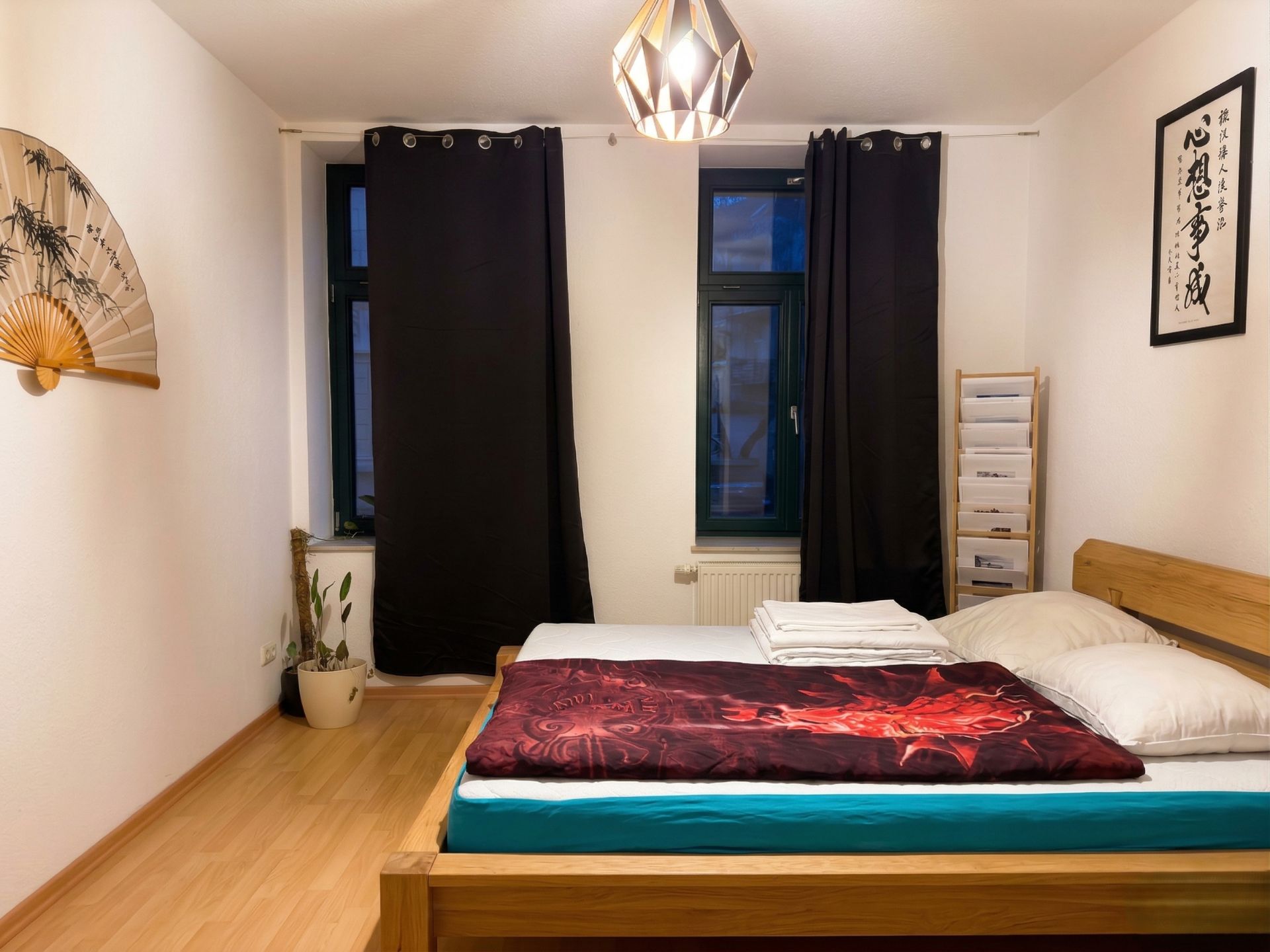 Schlafzimmer mit Doppelbett, Pflanzen, dunklen Vorhängen und Wanddekorationen.