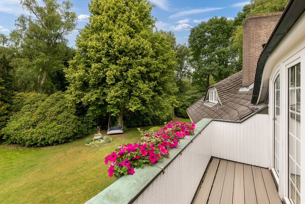 Balkon mit Blumenkasten, Blick auf einen Garten mit Bäumen und einer Schaukel.