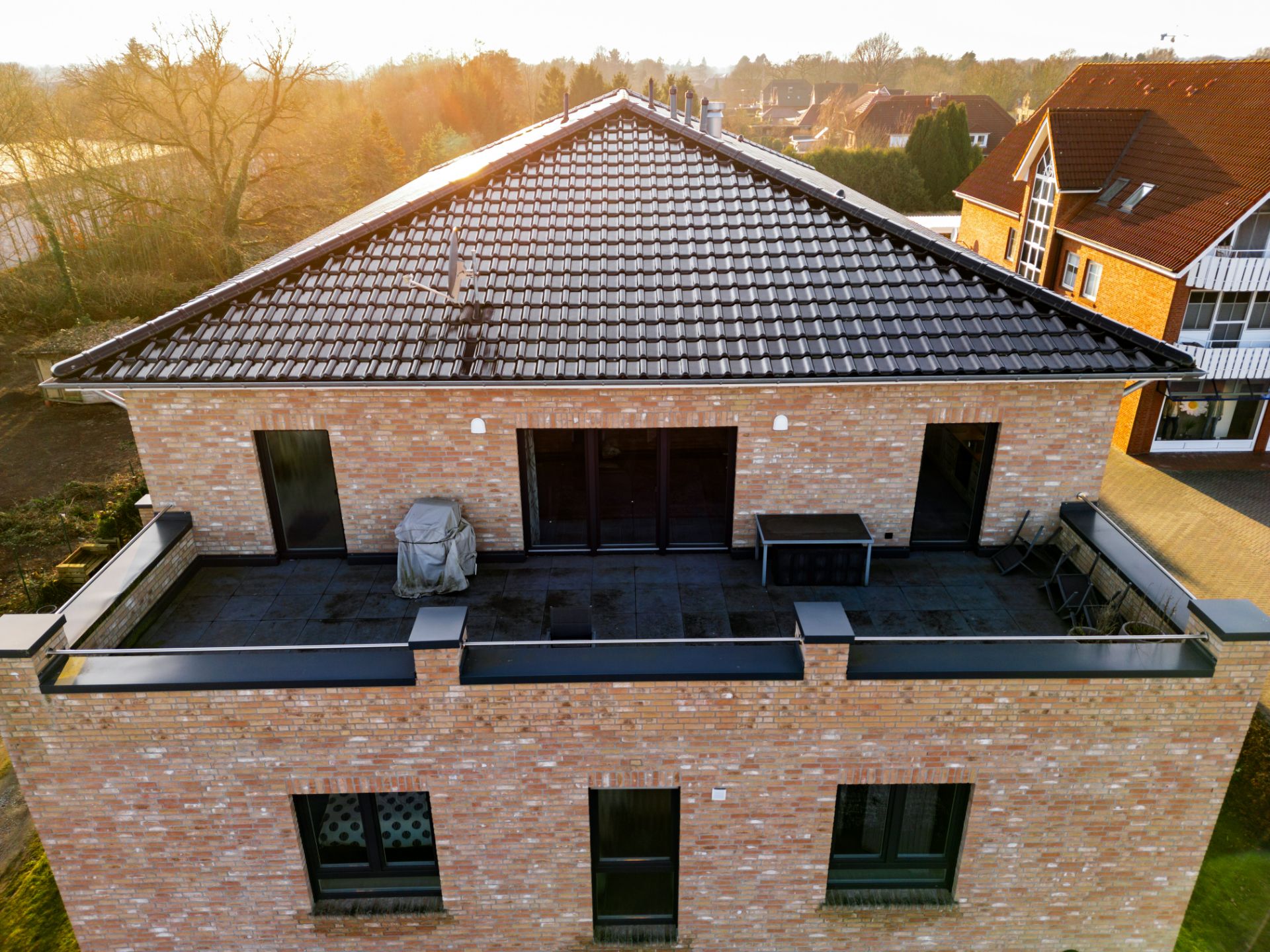 Backsteinwohnhaus mit großer Dachterrasse und Fliesenboden, Blick von oben.