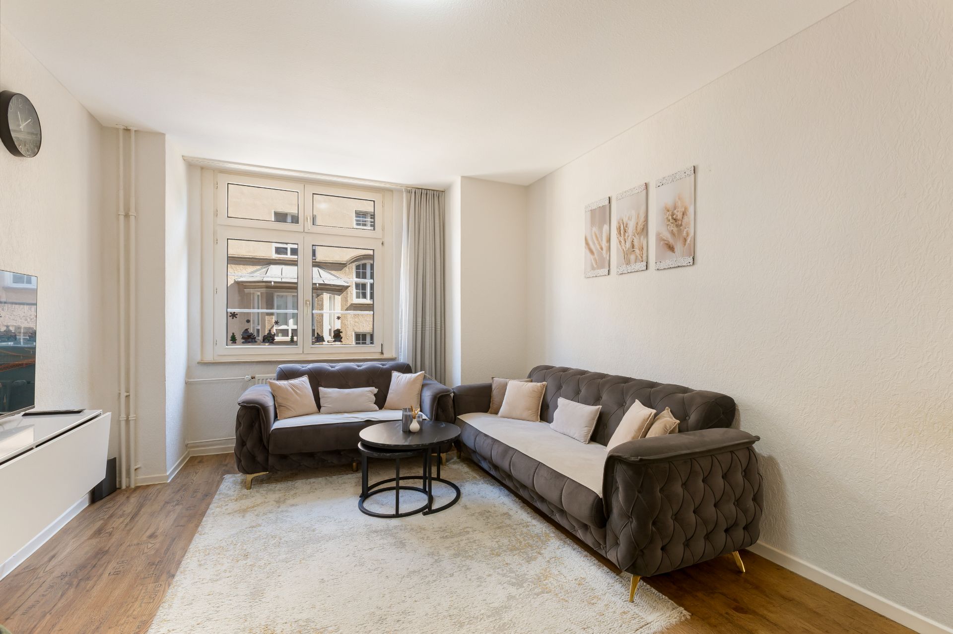 Helles Wohnzimmer mit zwei Sofas, Couchtisch, Teppich und großem Fenster.