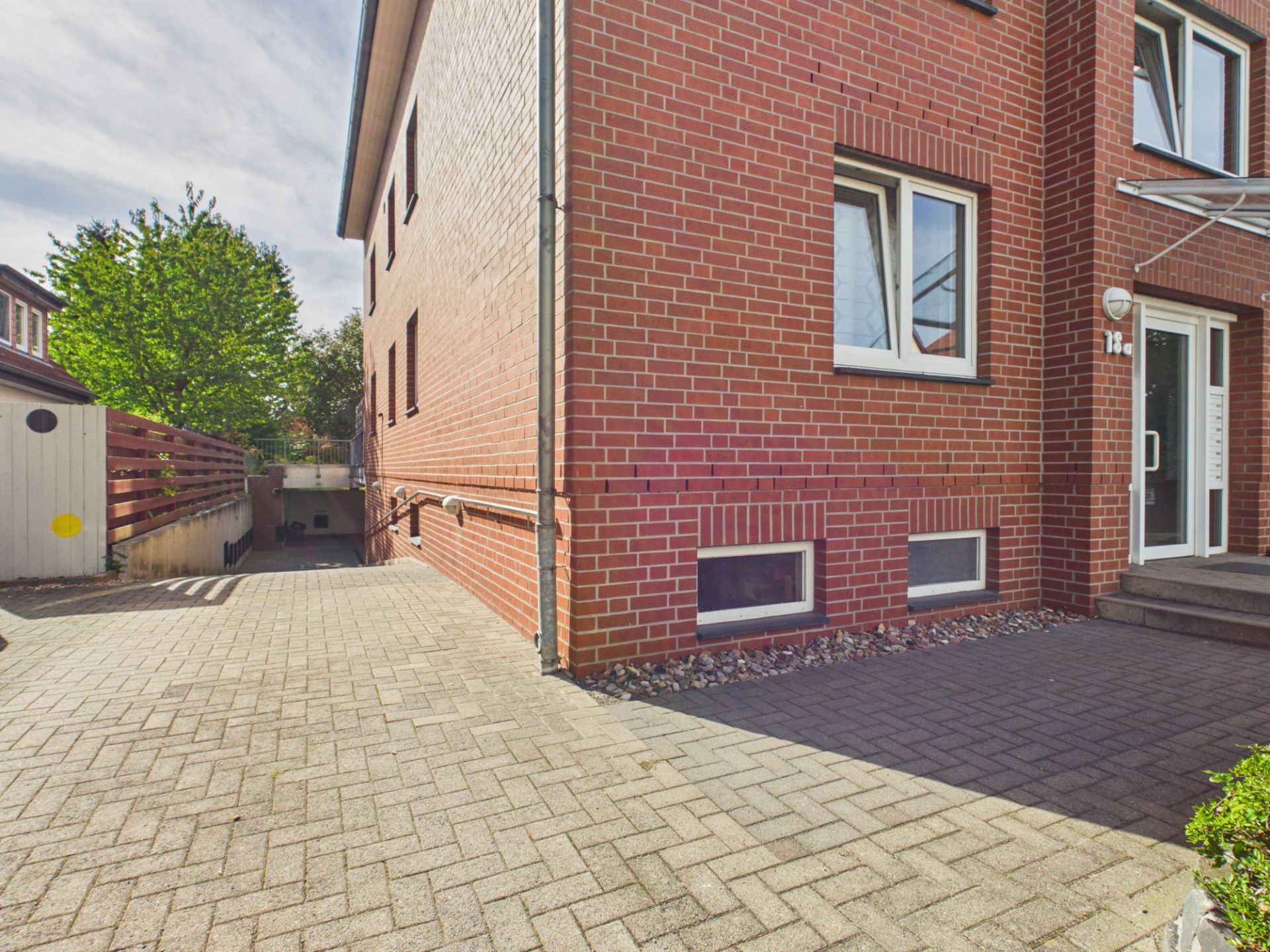 Backsteinwohnhaus mit gepflastertem Hof und Zugang zur Kellertreppe.