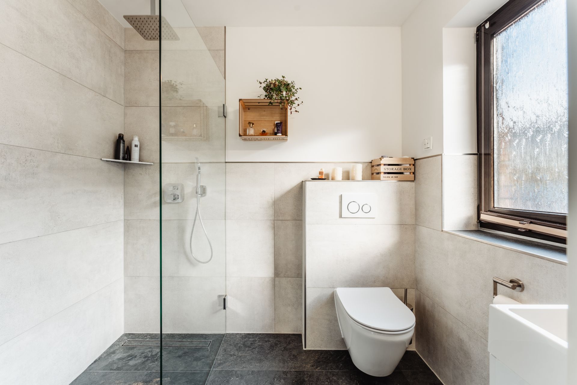 Modernes Badezimmer mit bodengleicher Dusche, Wandtoilette und großem Fenster.