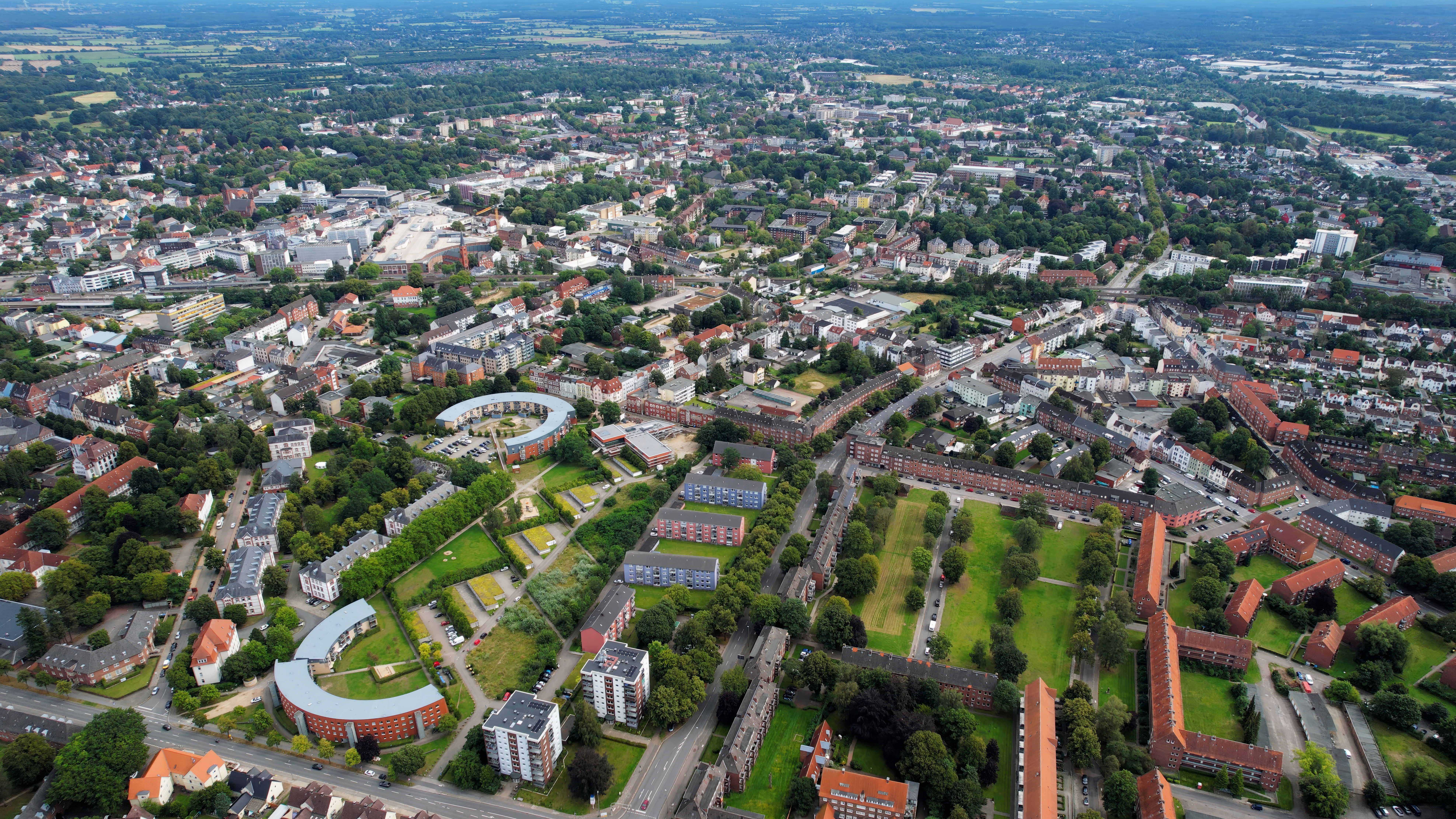 Luftaufnahme einer Wohnsiedlung mit mehreren Häusern, Bäumen und Straßen.