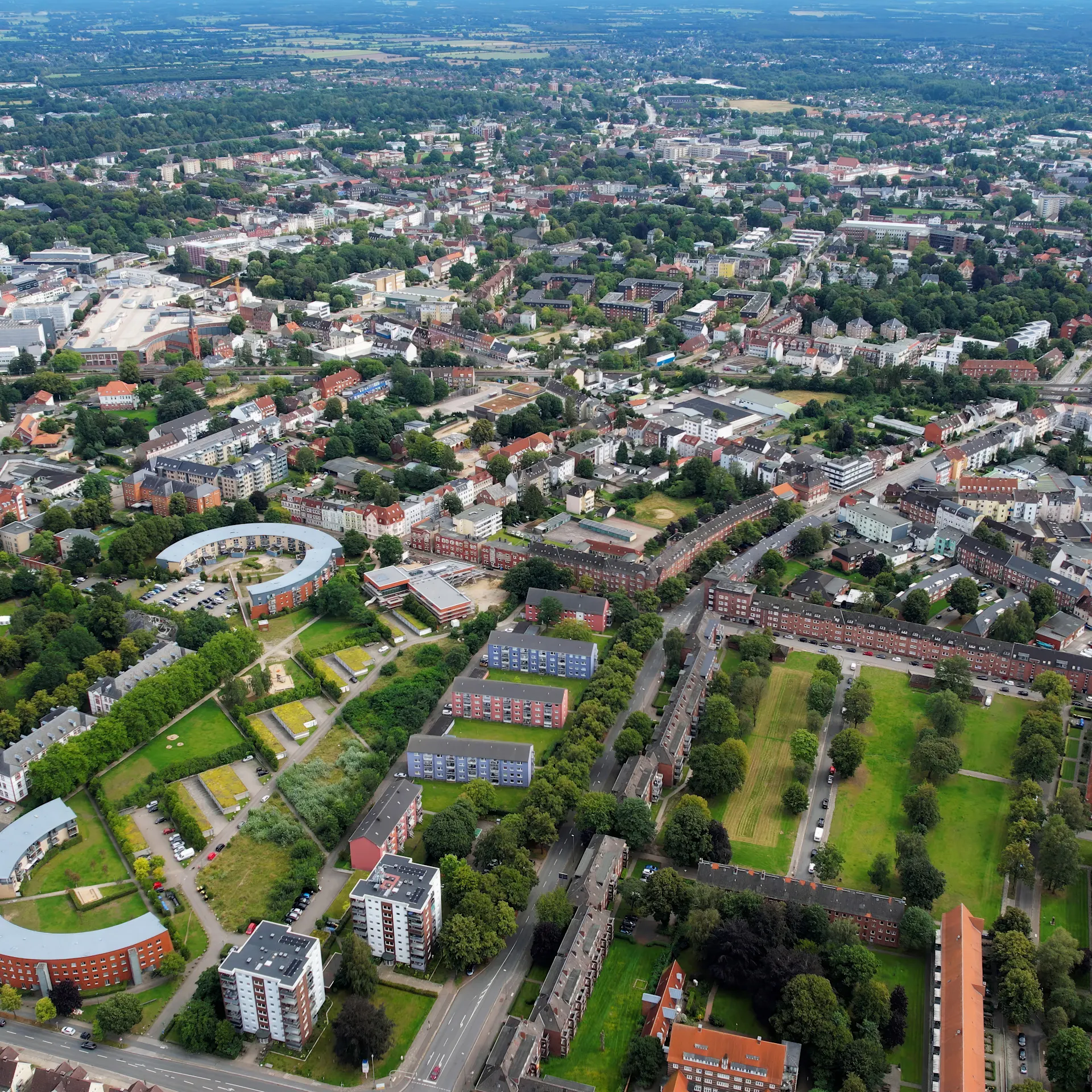 Luftaufnahme einer Wohnsiedlung mit mehreren Häusern, Bäumen und Straßen.