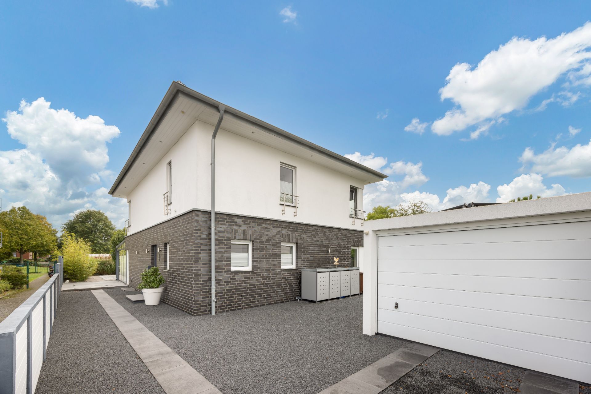 Modernes Wohnhaus mit gepflasterter Einfahrt und Garage bei Tageslicht.