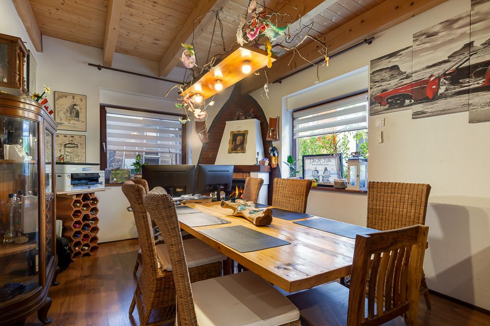 Esszimmer mit Holztisch, sechs Stühlen, dekorativer Lampe und großen Fenstern.