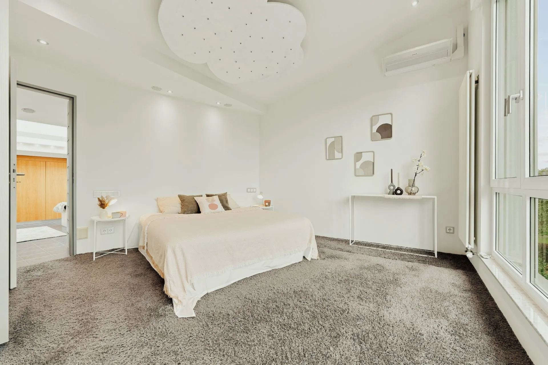 Helles Schlafzimmer mit Doppelbett, Teppichboden, großem Fenster und moderner Dekoration.