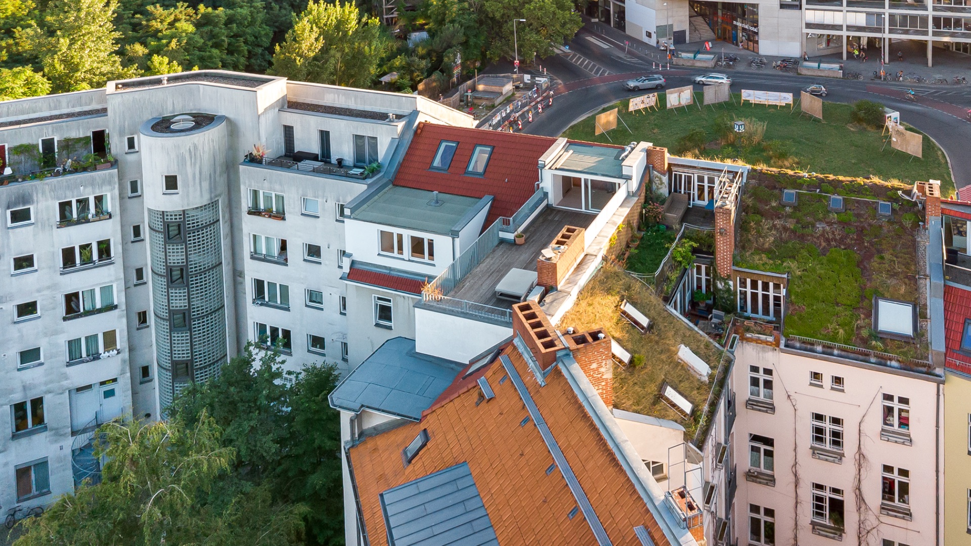 Mehrstöckige Wohngebäude mit begrünten und begehbaren Dächern in einer grünen Stadtumgebung.