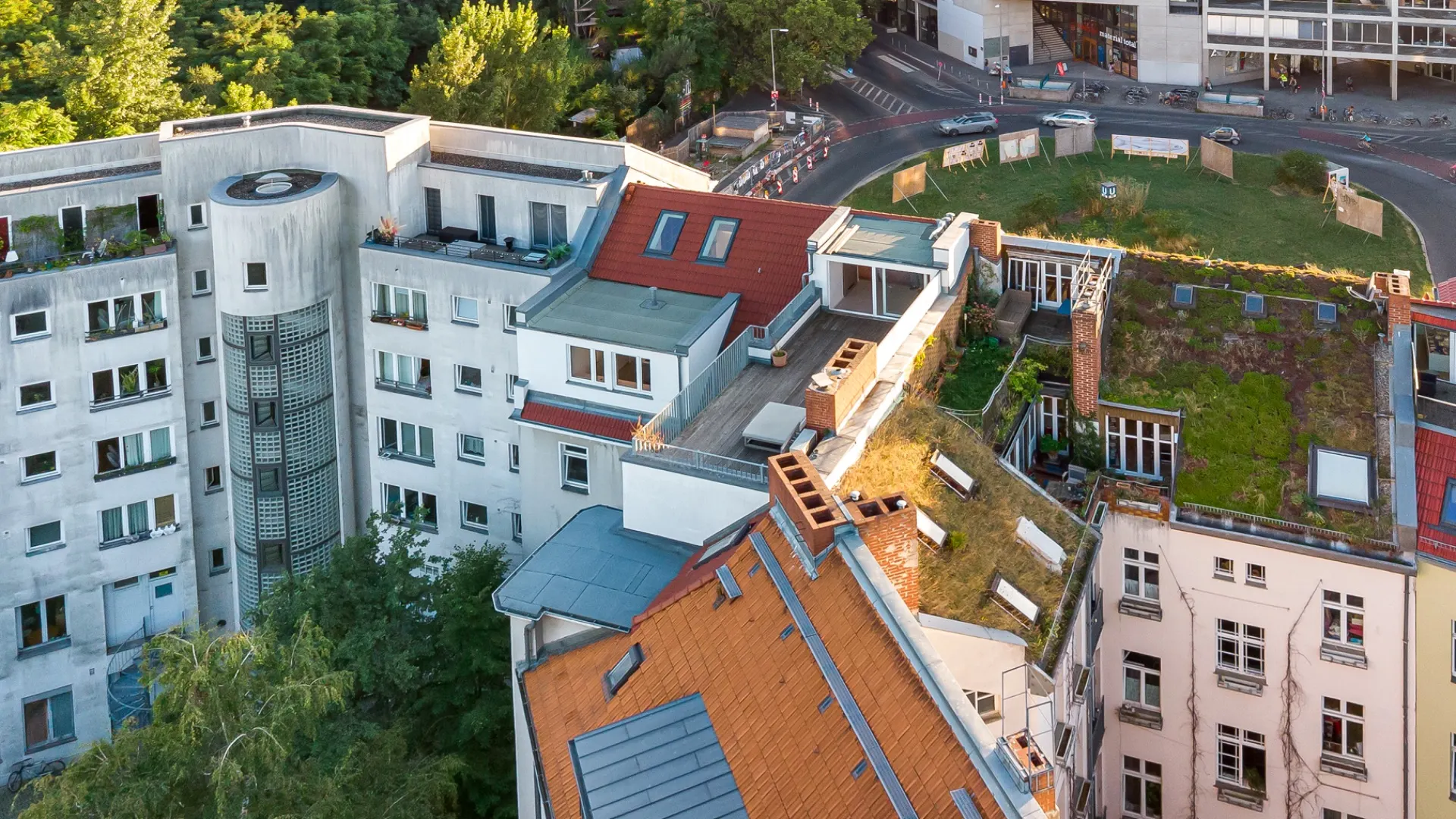 Mehrstöckige Wohngebäude mit begrünten und begehbaren Dächern in einer grünen Stadtumgebung.