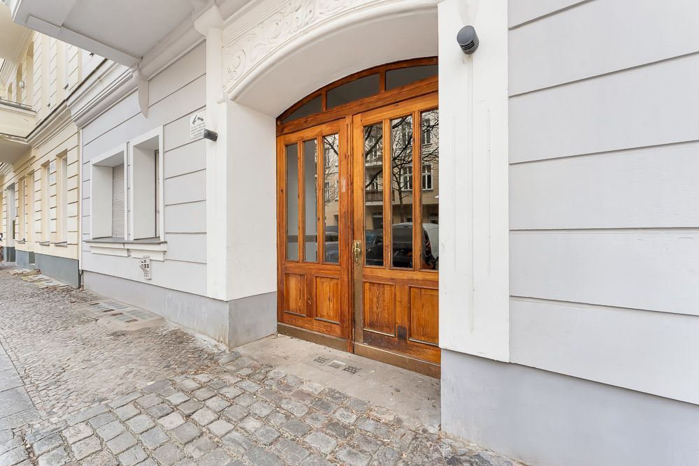 Holztür mit Glasfenstern am Eingang eines Wohnhauses, Kopfsteinpflaster davor.
