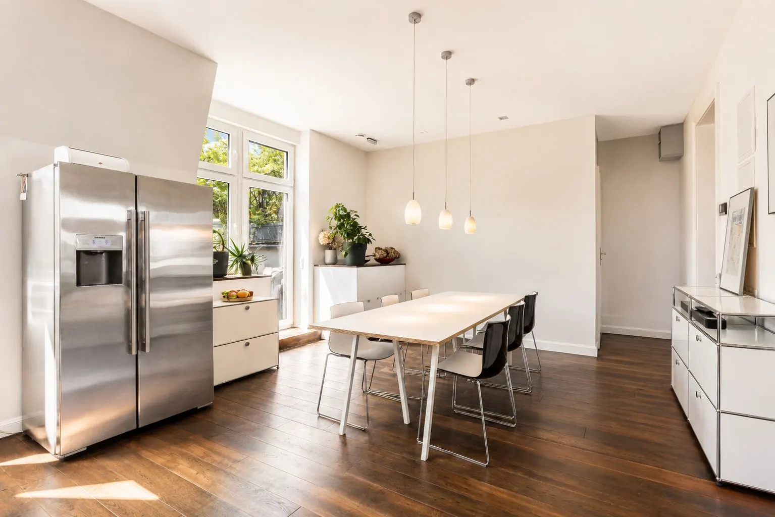 Heller Essbereich mit Holzboden, großem Kühlschrank und Tisch mit Stühlen.