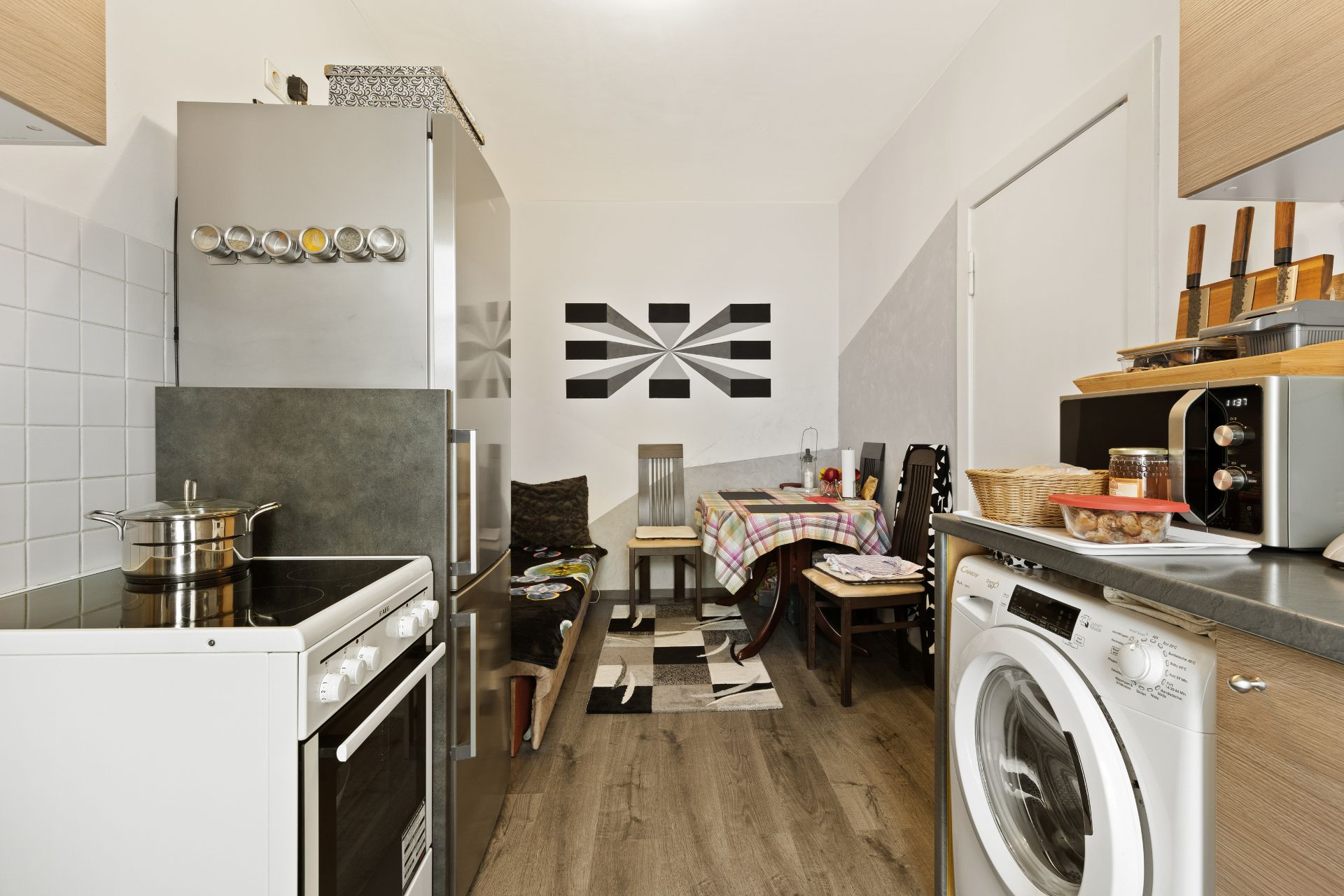 Küche mit Esstisch, Waschmaschine, Herd, Kühlschrank und Wanddeko.