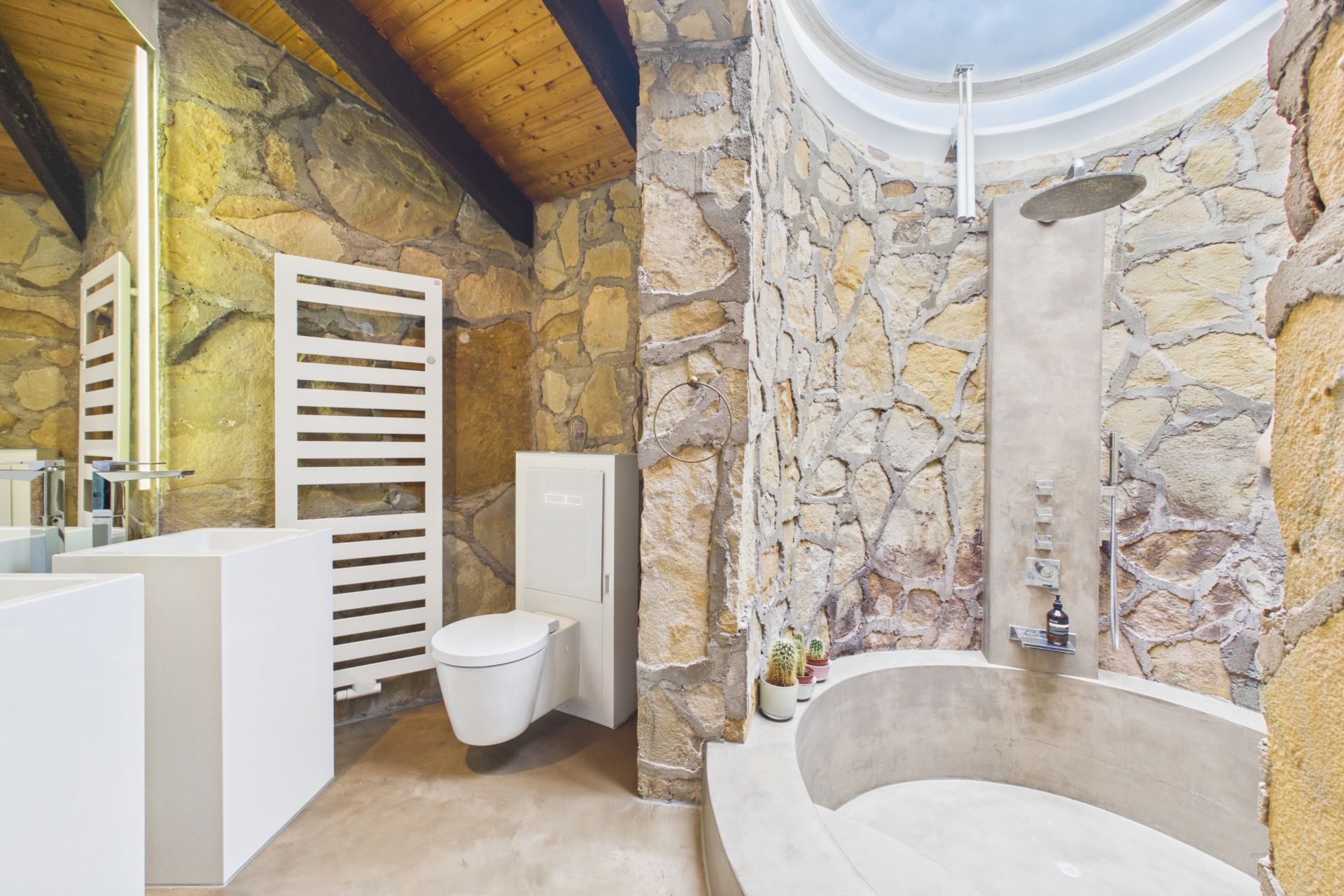 Modernes Badezimmer mit Steinwänden, großer Dusche, WC und Waschtisch unter Holzdecke.