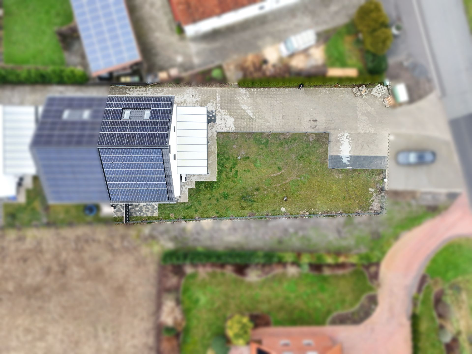 Luftaufnahme eines modernen Hauses mit Solarpanels und angrenzendem Garten.