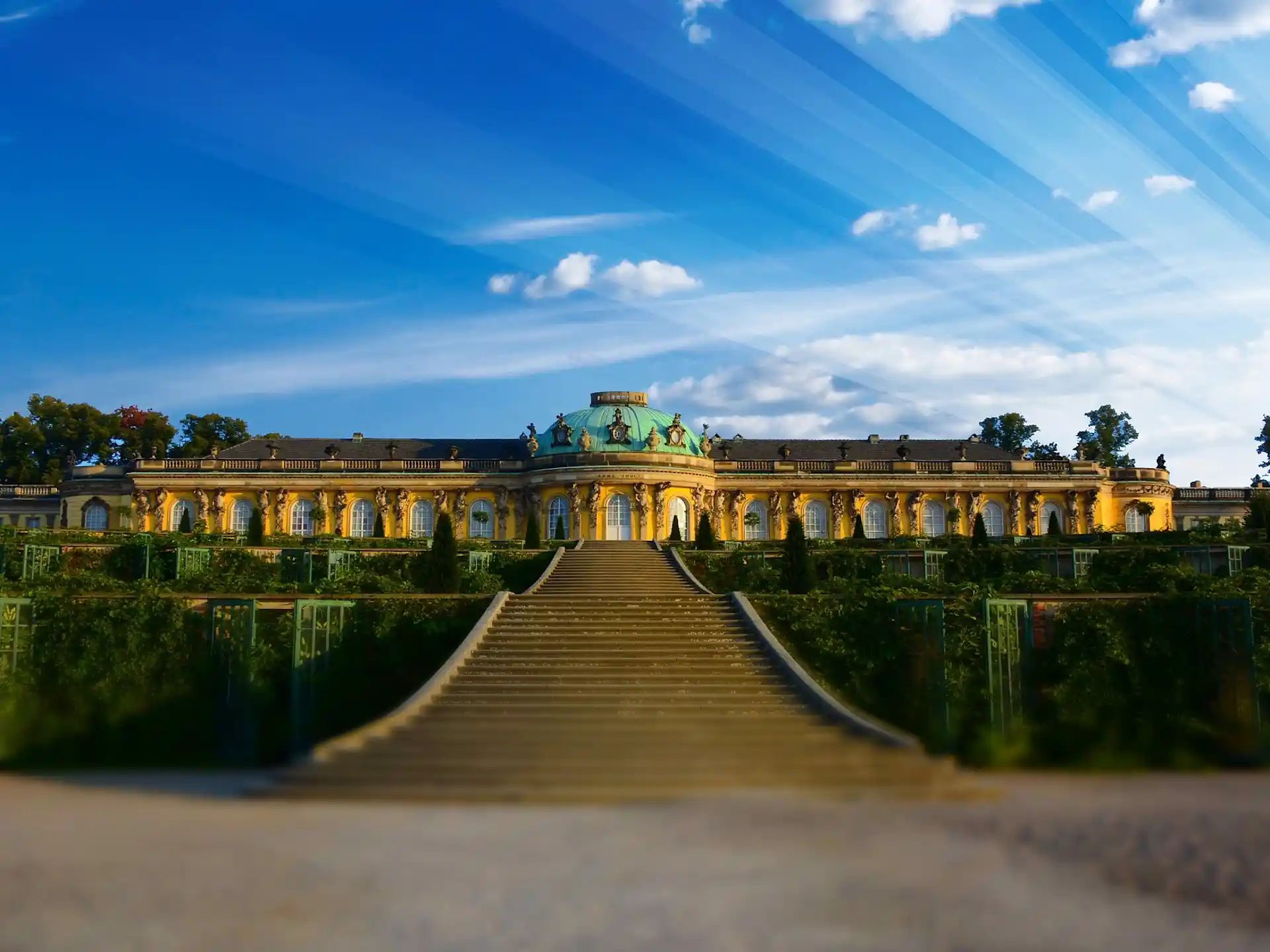 Großes, gelbes Wohngebäude mit verzierten Fenstern und breiter Treppe im Vordergrund.